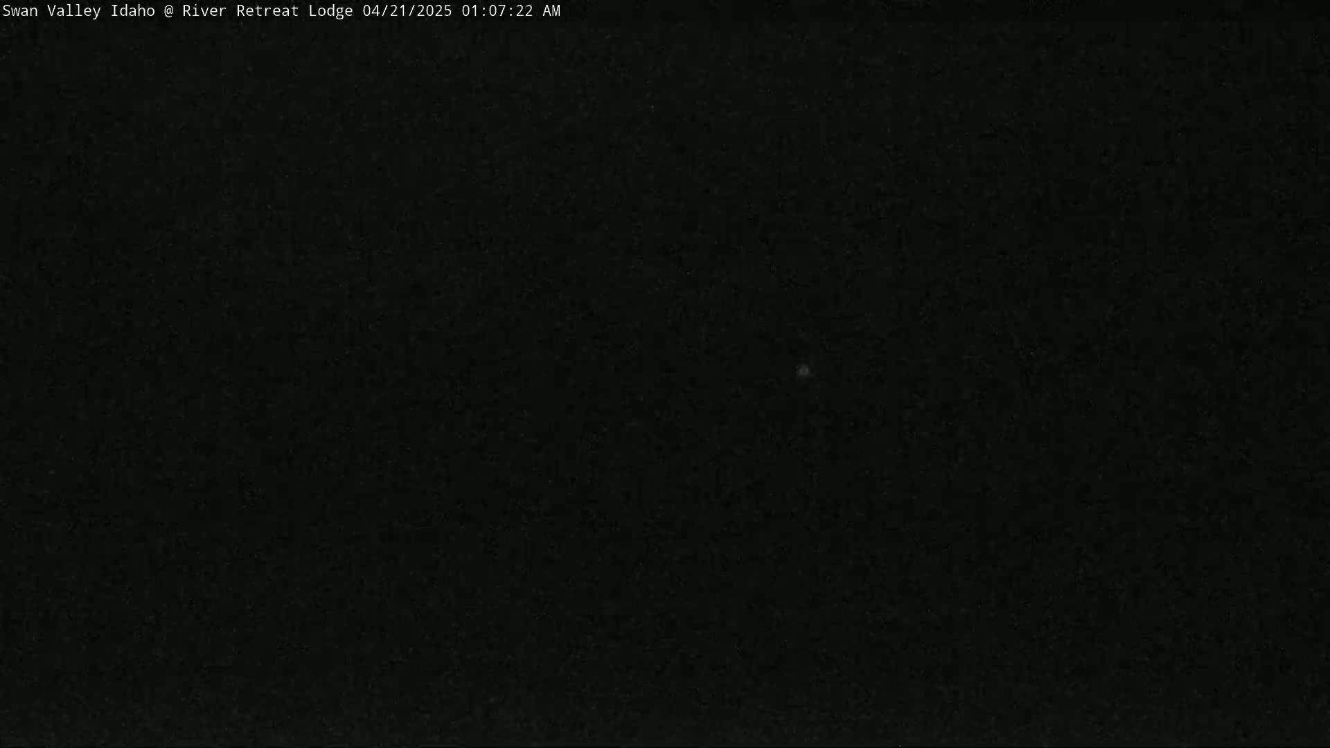 A dark, nighttime image shows a mostly black sky with a few faint specks of light.