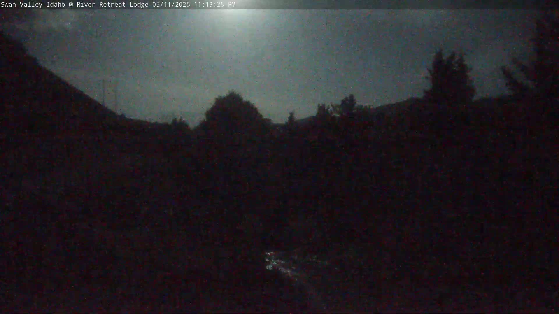 A dark, nighttime scene shows a stream flowing through a shadowy landscape under a dusky sky.