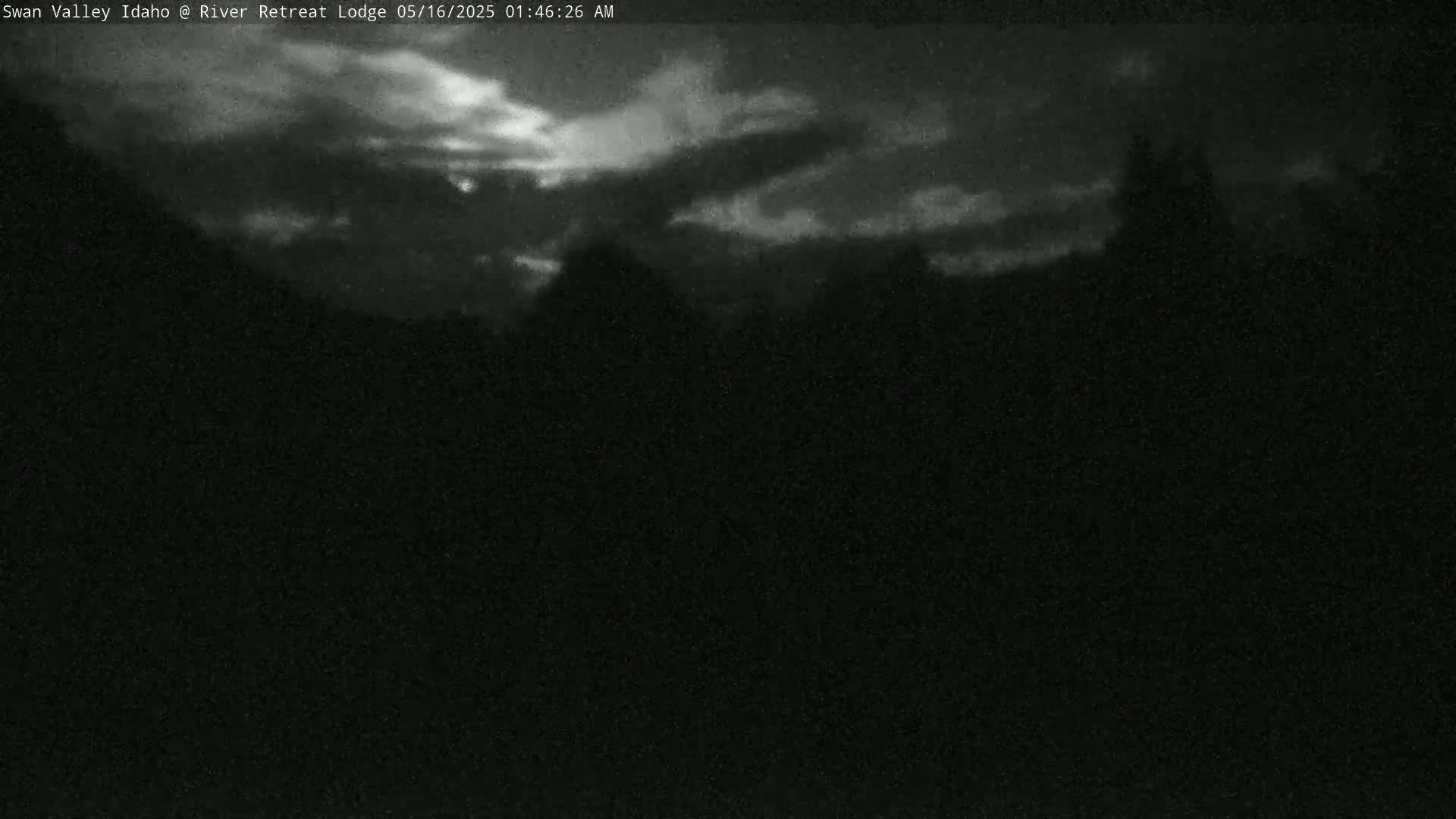 A nighttime, low-light outdoor scene shows a dark, cloudy sky above a silhouetted landscape.