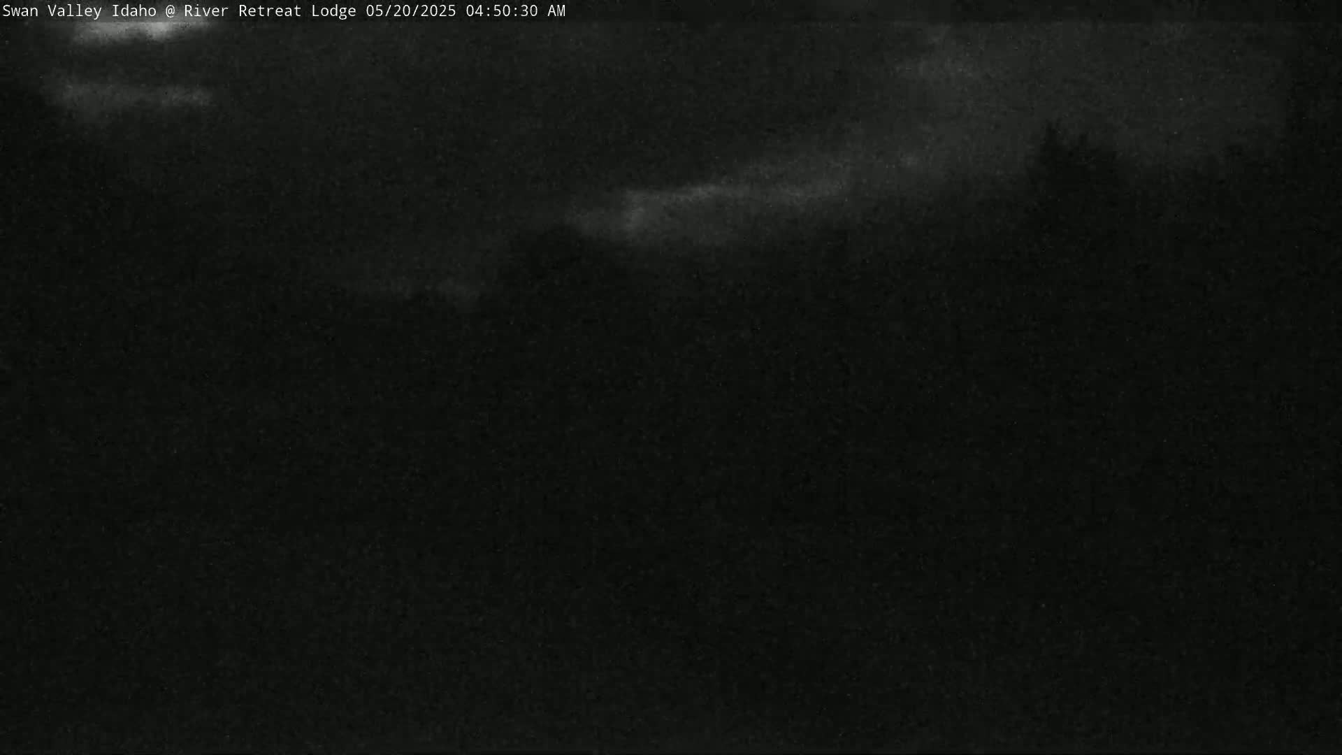 A dark, nighttime outdoor scene shows a mostly obscured landscape under a cloudy sky.