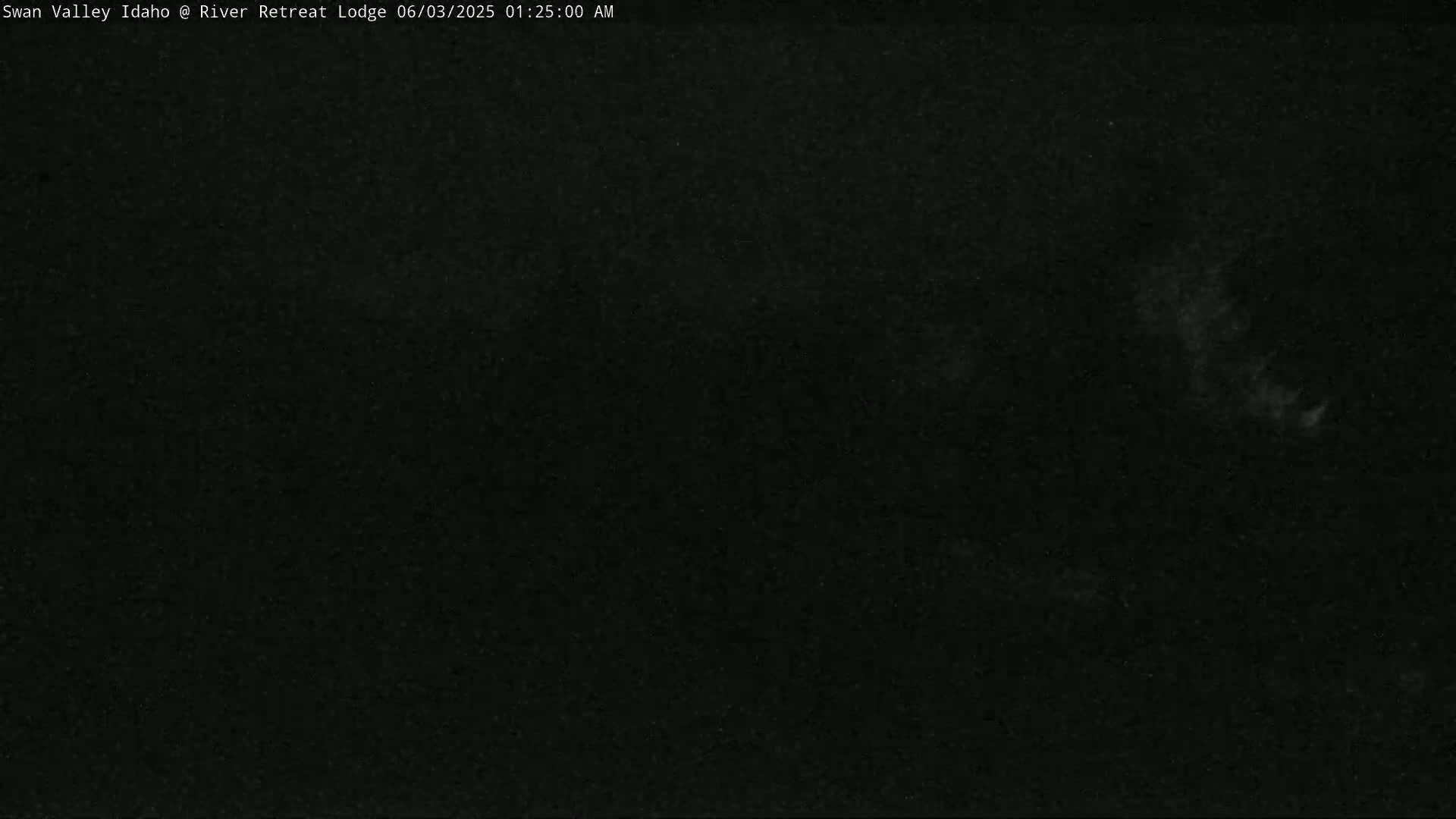 A very dark image shows a mostly black night sky with a few faint, indistinct white clouds.