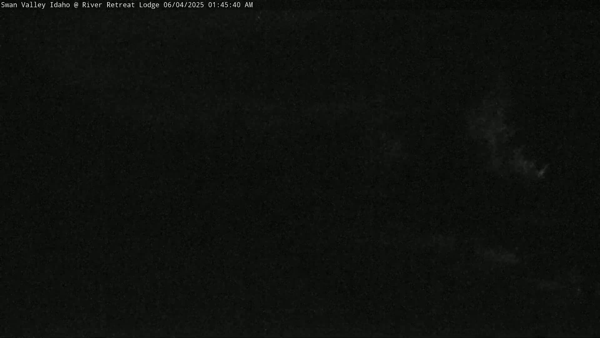 A nighttime, dark image shows a mostly clear sky with some faint clouds.