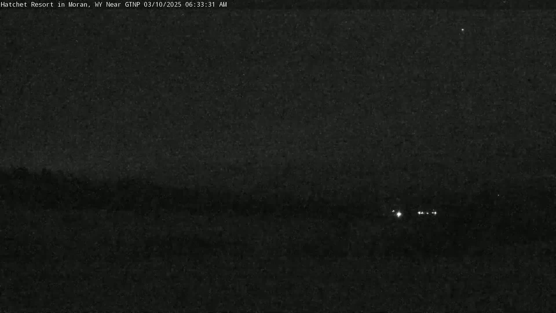 A nighttime, low-light view shows a dark landscape with a few distant lights.