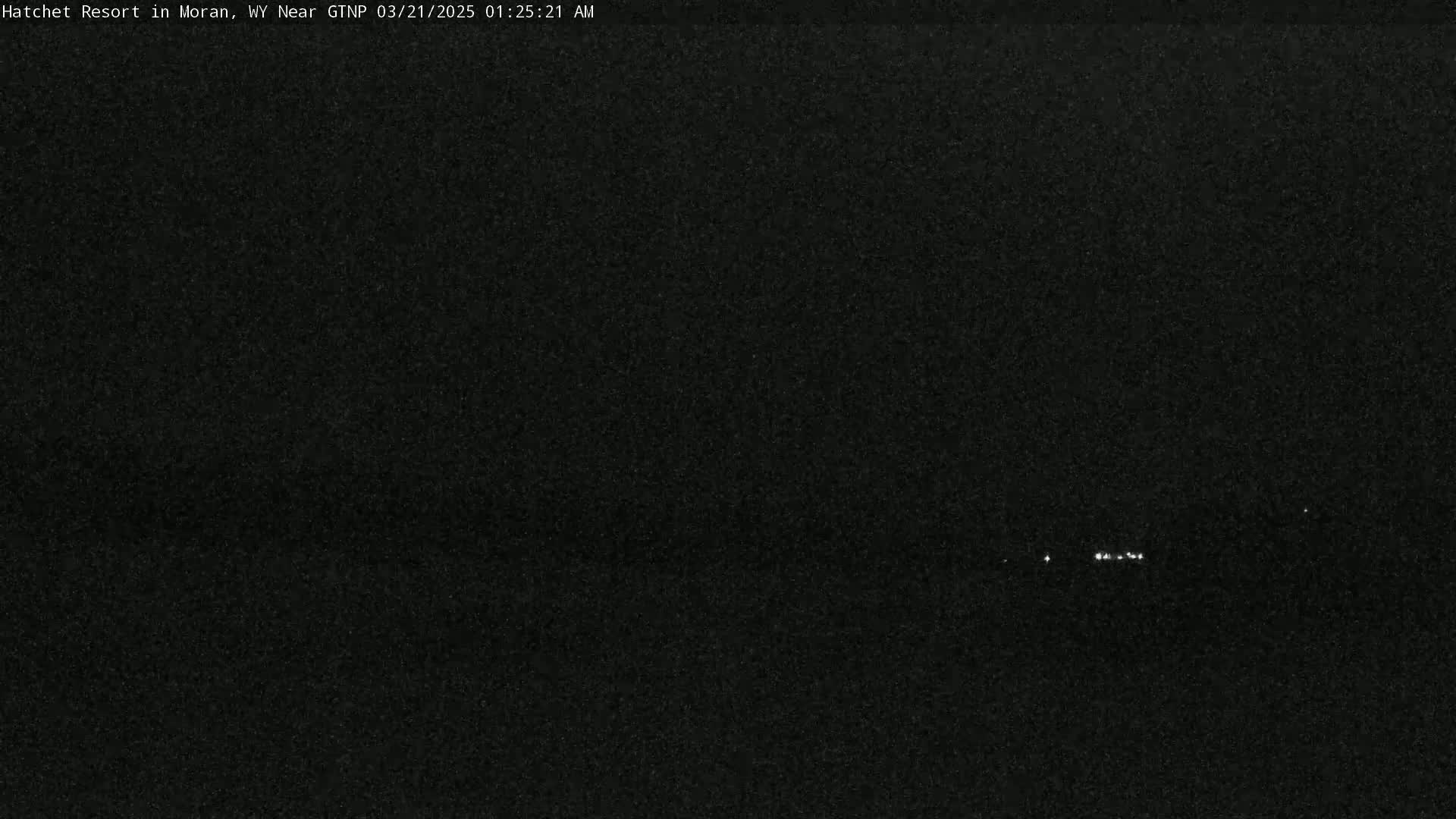 A nighttime long shot shows a few distant lights against a dark, grainy sky.