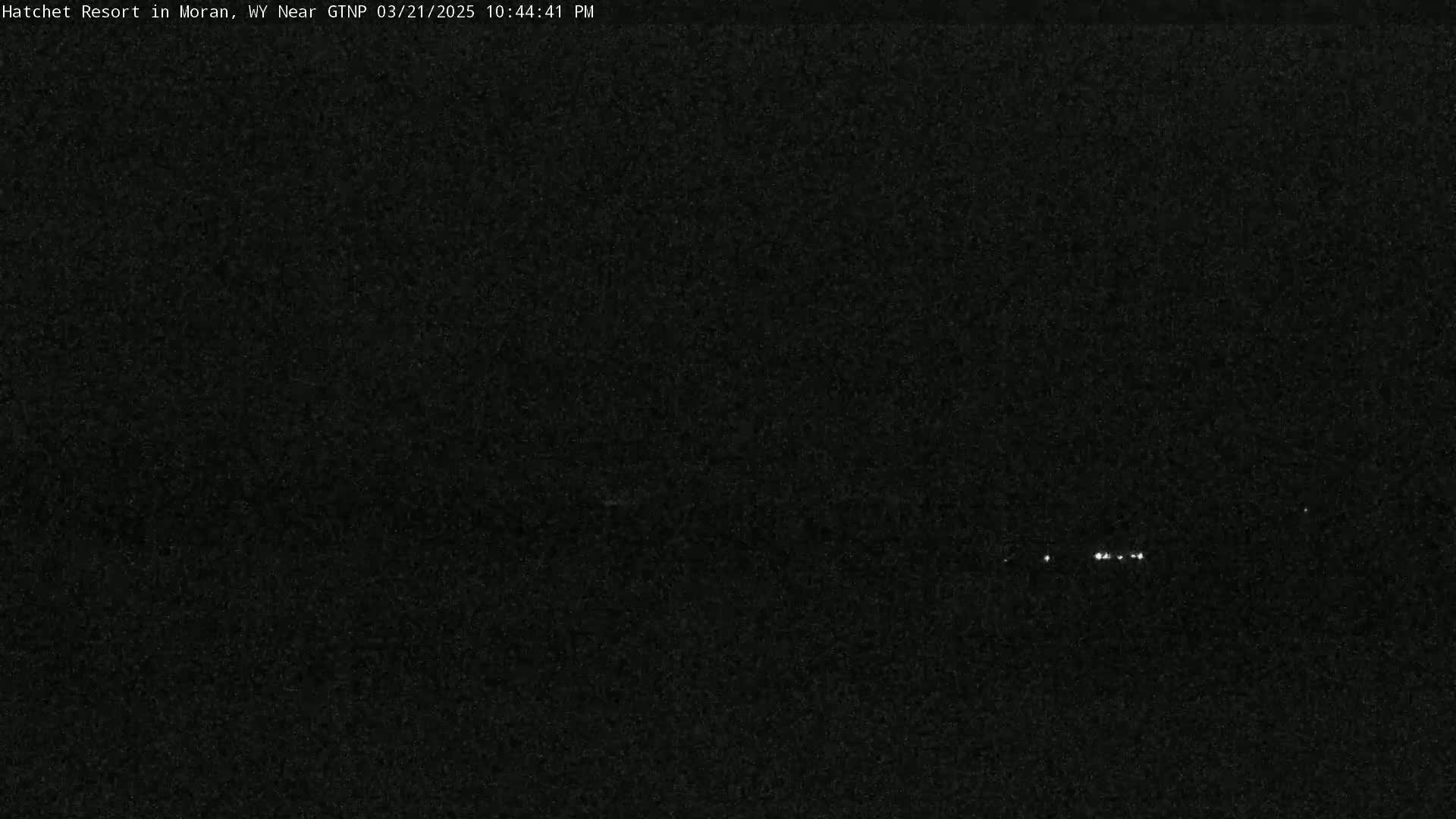 A nighttime, dark image shows a few small, distant lights in the center.