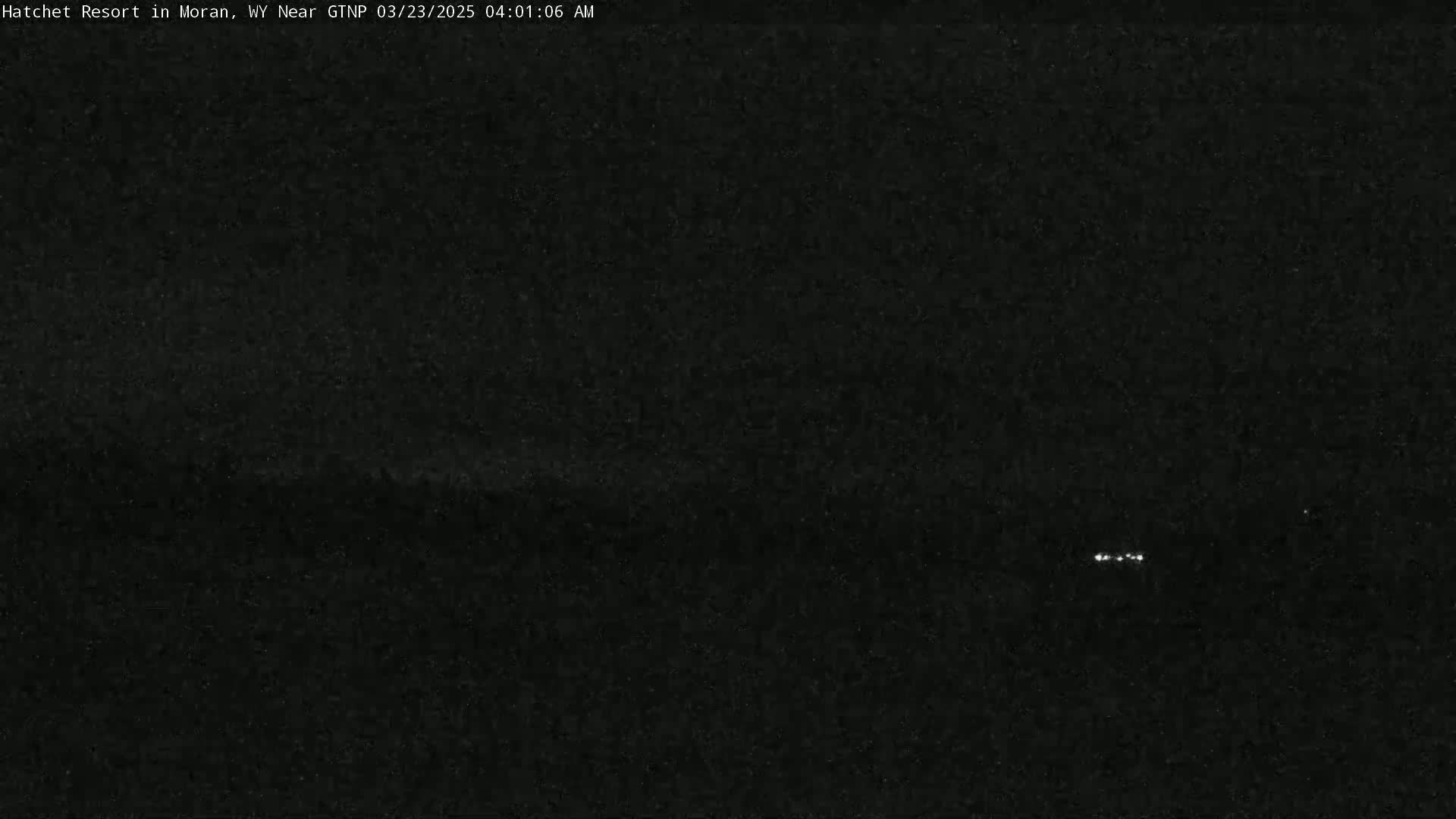 A dark, nighttime scene shows a few faint lights in the distance.