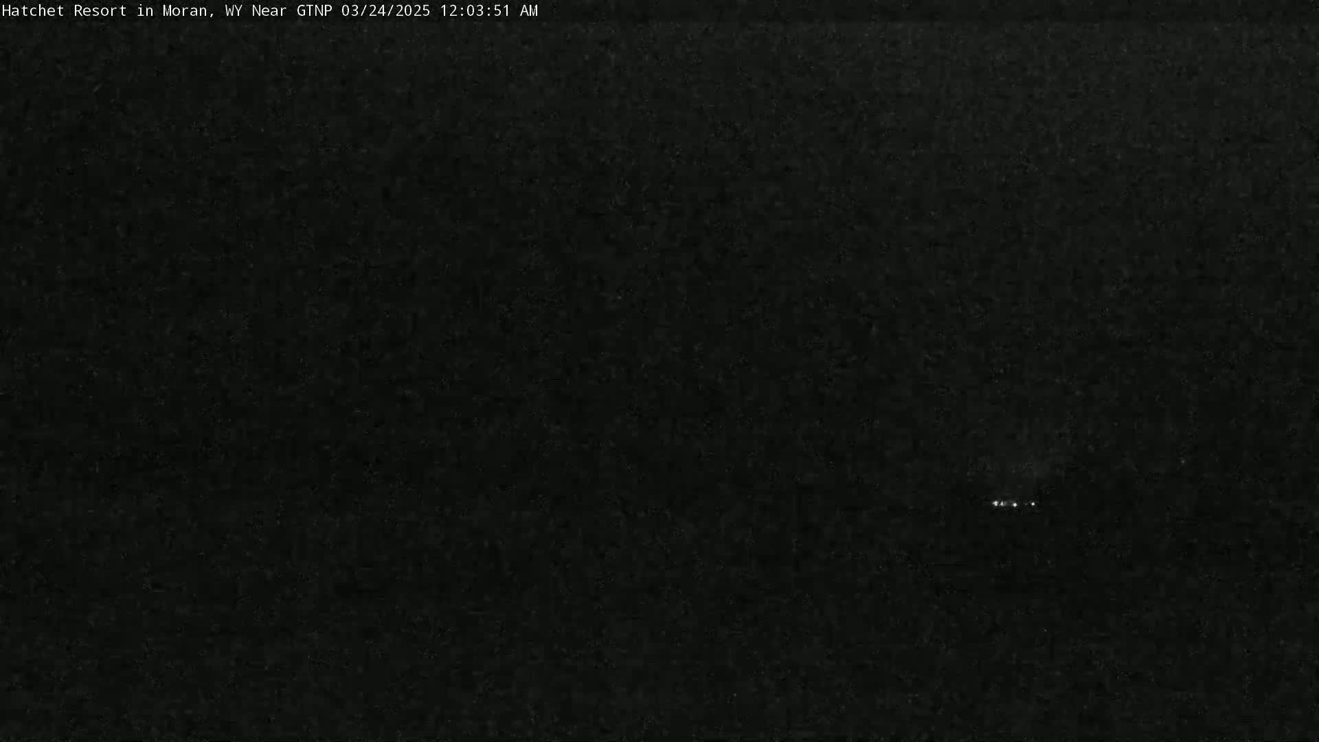 A dark, nighttime image shows a few faint lights in the distance.