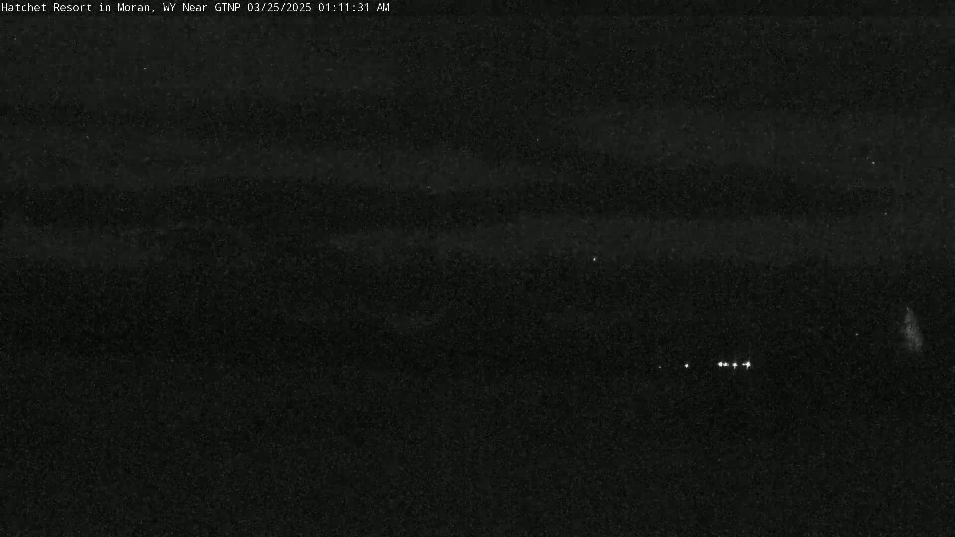 A nighttime long shot shows a dark, mostly clear sky with a few distant, small lights visible on the horizon.