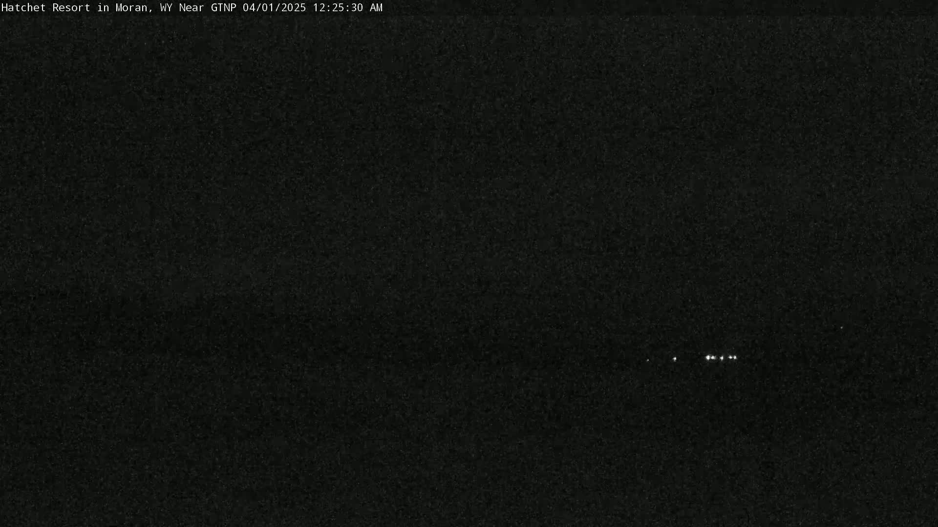 A nighttime, low-light image shows a few small, distant lights in the center.