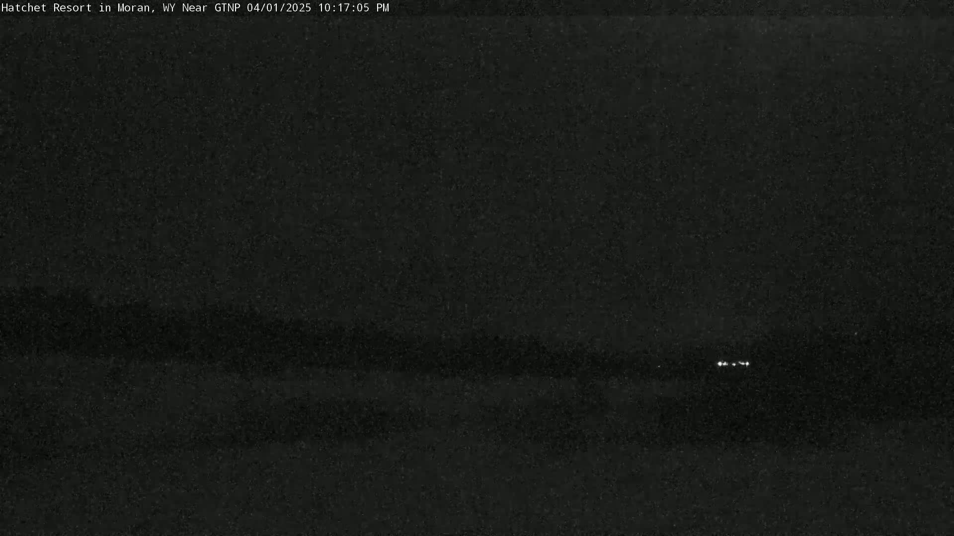 A dark, nighttime scene shows a few faint lights in the distance.