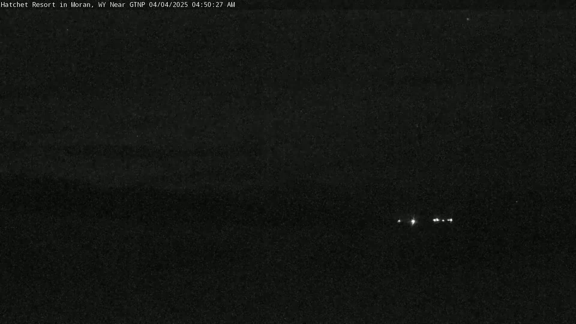 A dark, nighttime scene shows a few small, distant lights in the center.