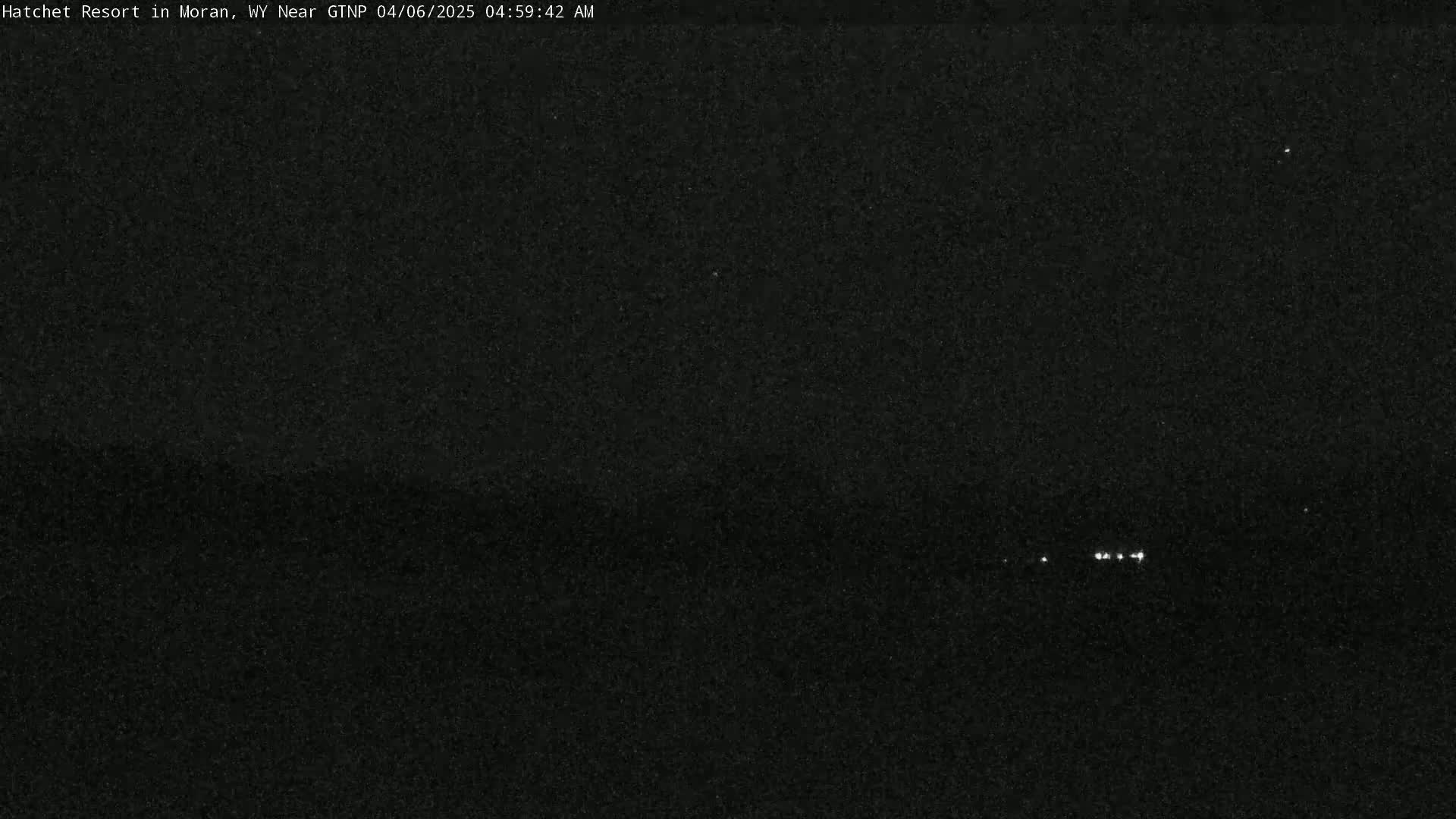 A dark, nighttime scene shows a few faint lights in the distance.