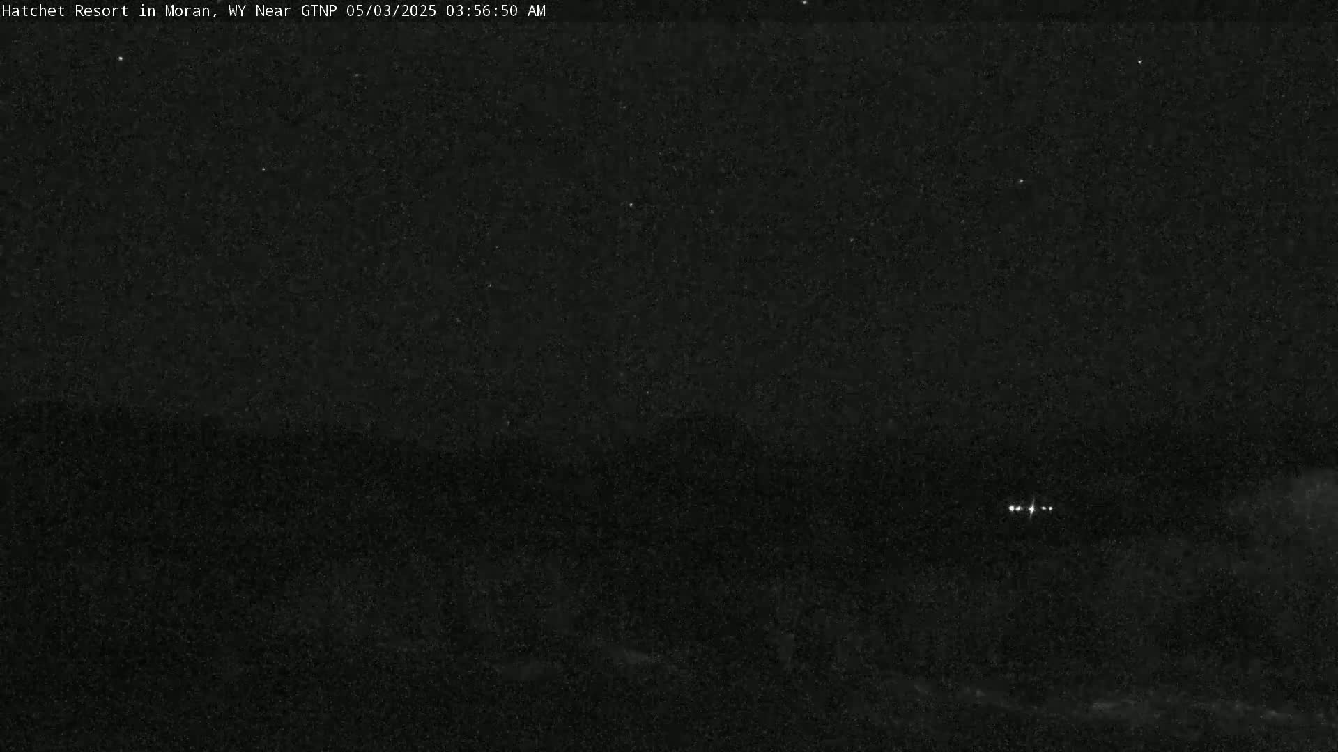 A nighttime, dark landscape is visible under a clear, starry sky with a few distant lights.