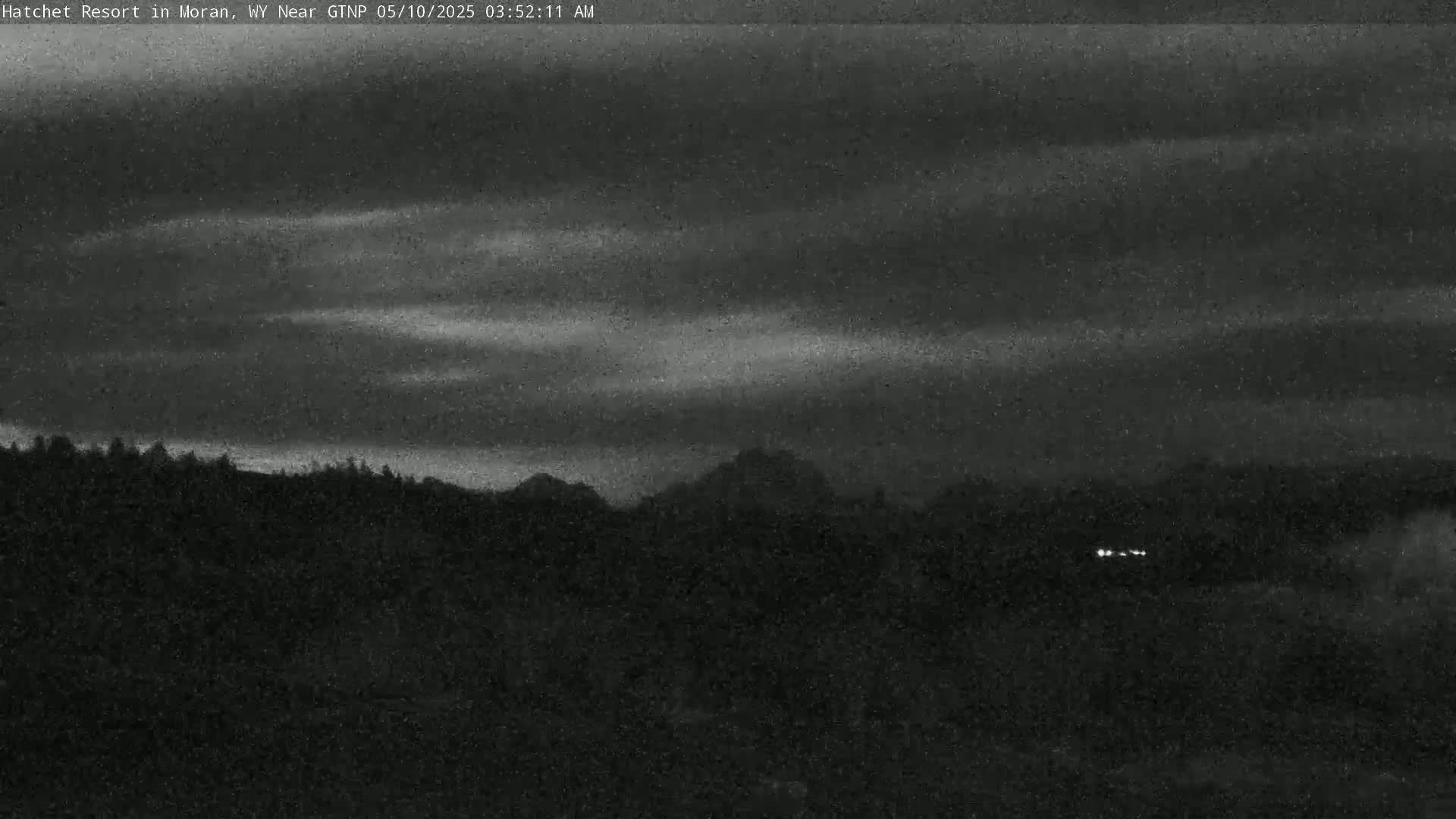 A dark, overcast sky over a silhouetted mountain range and trees.