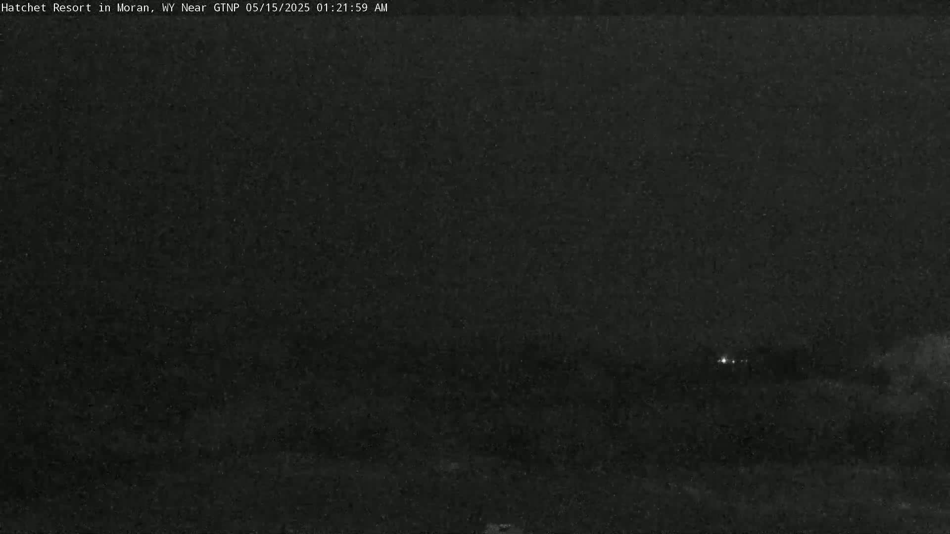 A dark, nighttime scene shows a few distant lights in the center, under a mostly clear sky.