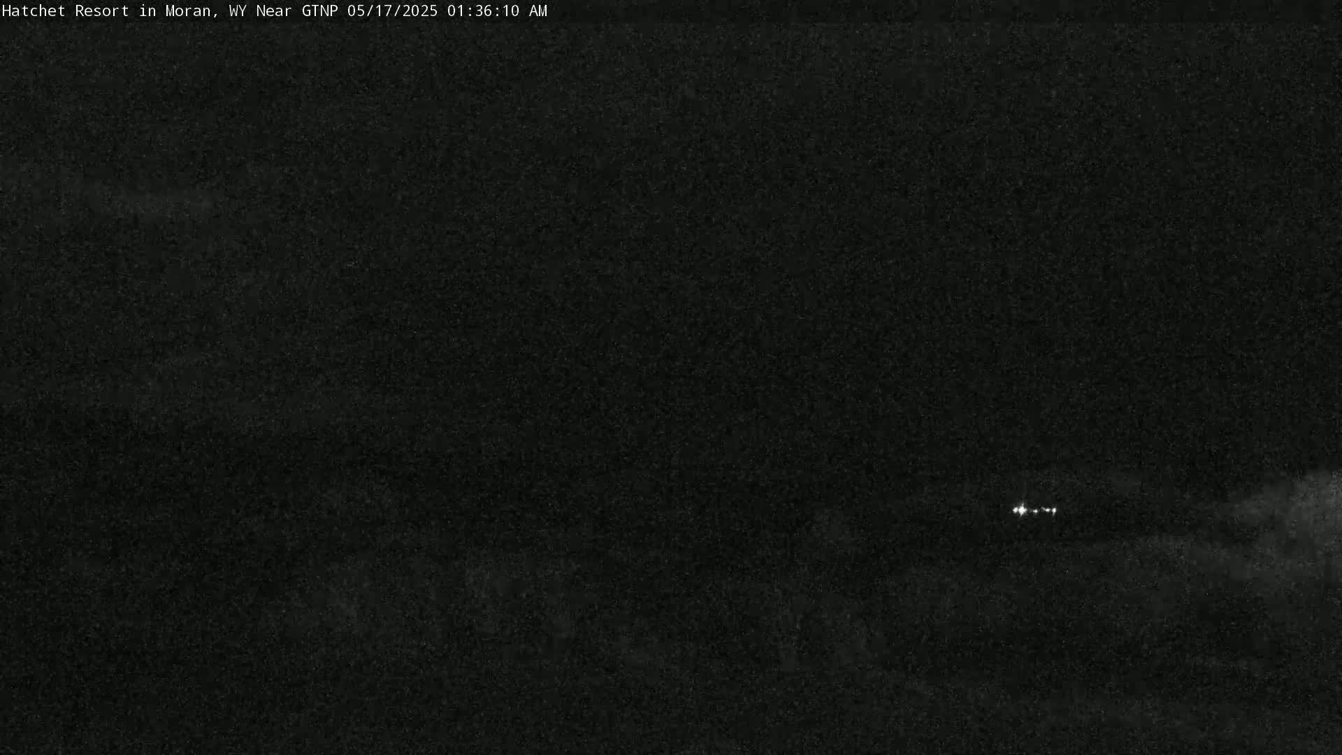 A nighttime, low-light view shows a dark landscape with a few distant lights.