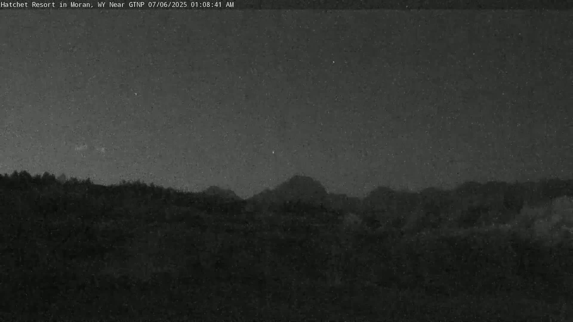 A nighttime view shows dark, silhouetted hills under a clear, starry sky.