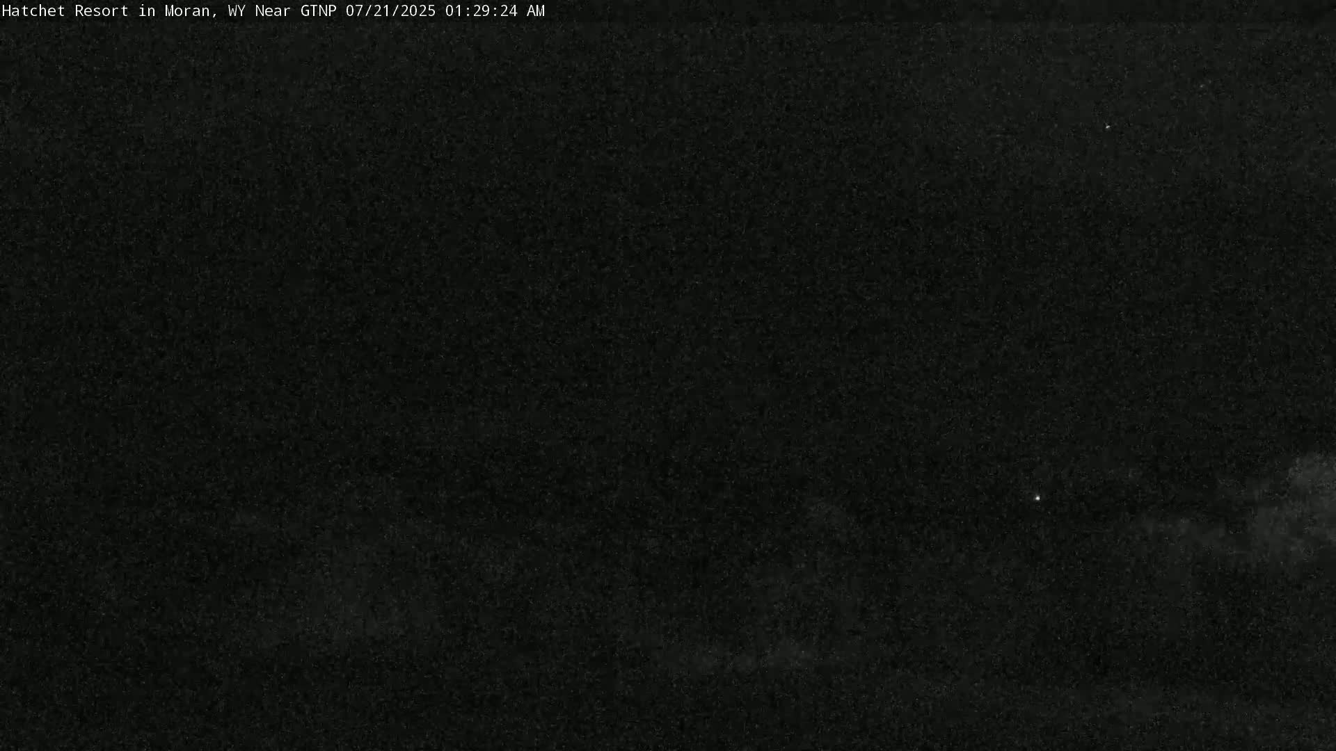 A dark, nighttime outdoor scene with a few faint lights visible in the distance.
