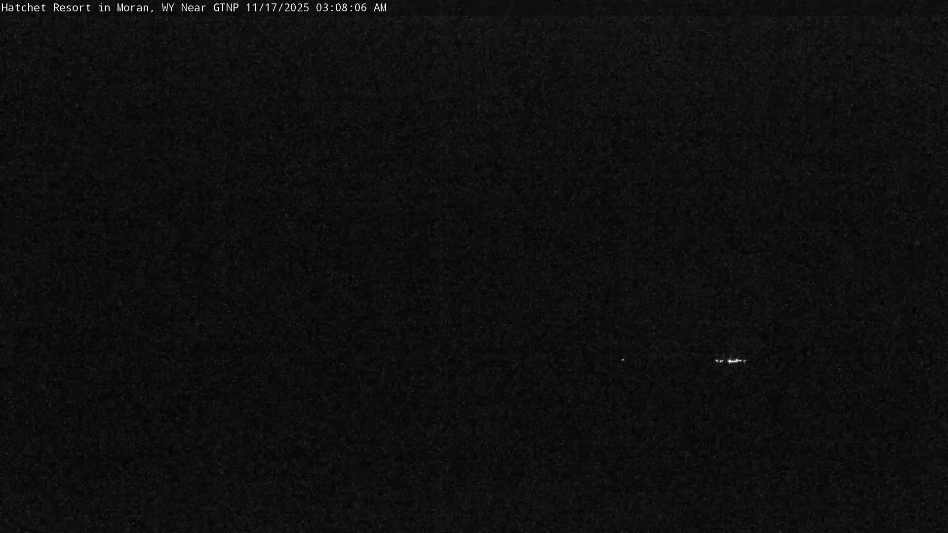 The outdoor scene is almost completely dark, likely due to nighttime, with only a few very faint, distant white lights visible towards the lower right, making weather conditions indiscernible.