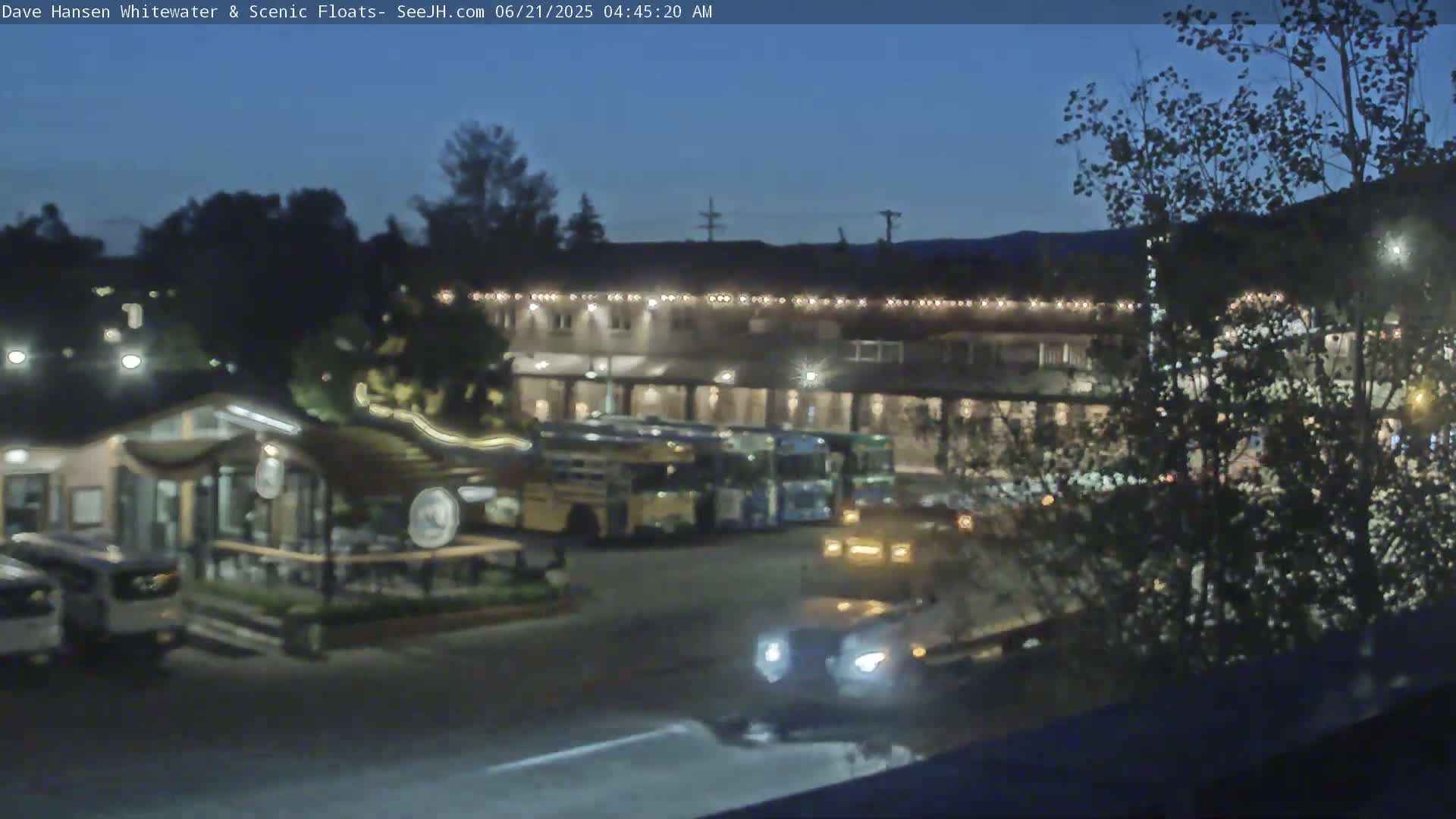 A nighttime view of a parking lot with several vehicles and a building with lights, under a dark blue sky.