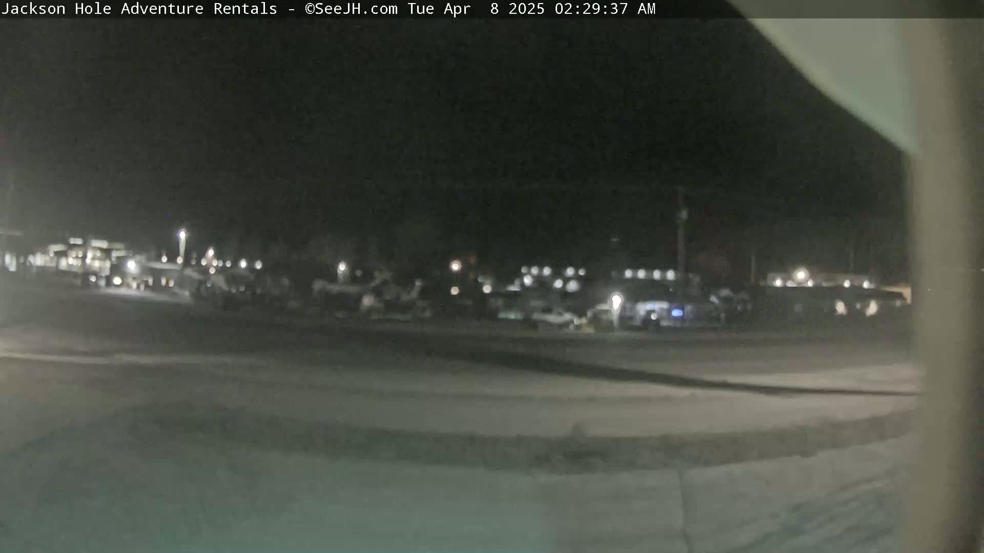 A nighttime, blurry view of a parking lot with several vehicles, under dark, clear skies.