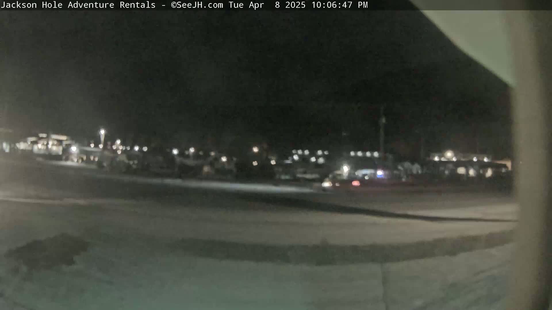 A nighttime, blurry view of a parking lot with numerous vehicles and lights.