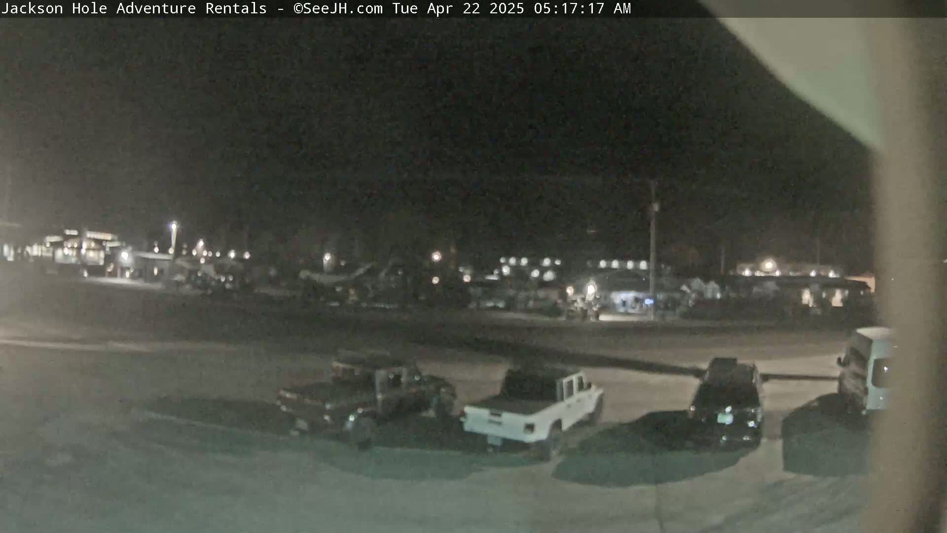 Several vehicles are parked in a dark, outdoor lot at night.