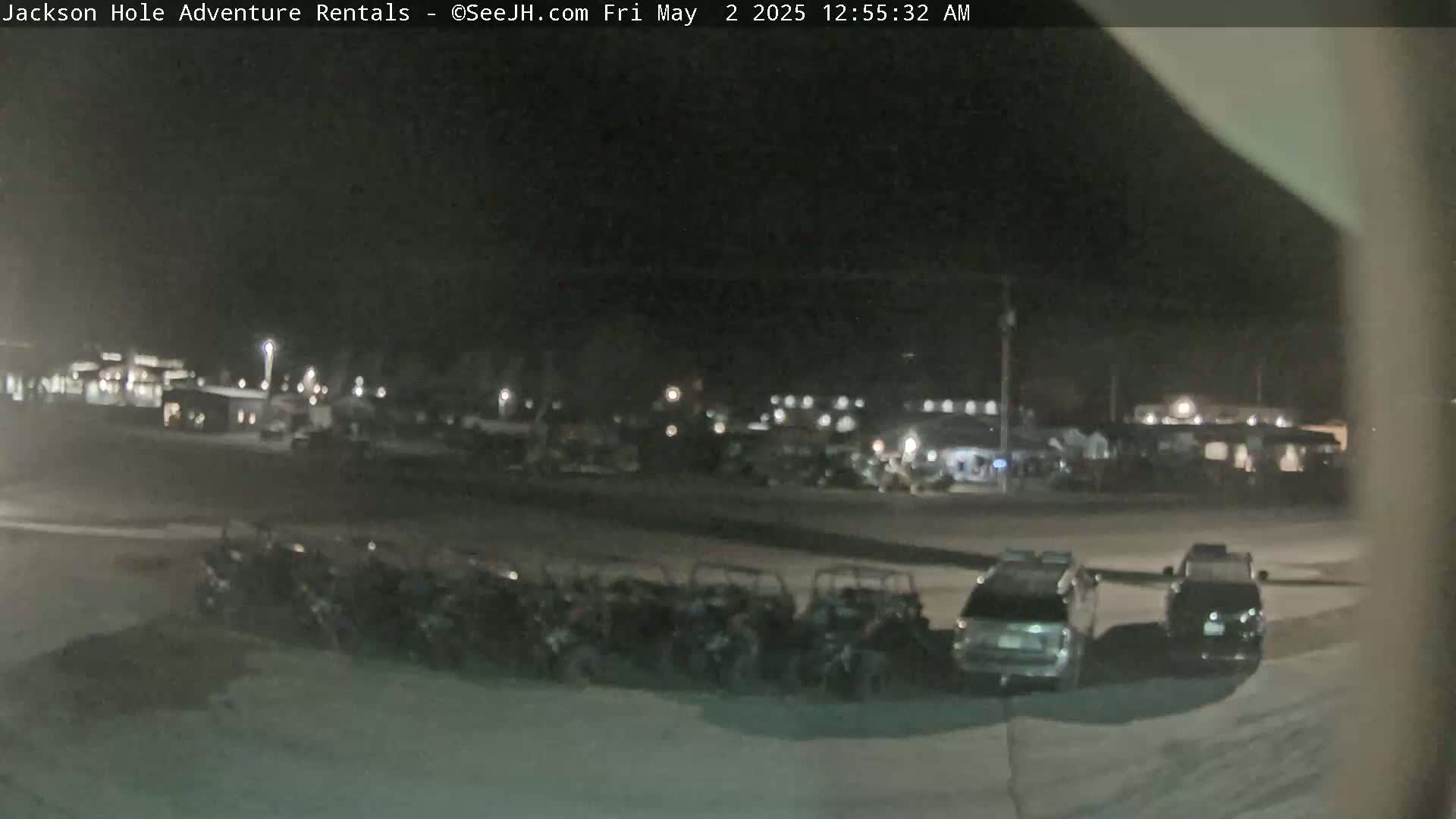 A nighttime outdoor scene shows a row of parked all-terrain vehicles in front of several buildings under dark, clear skies.