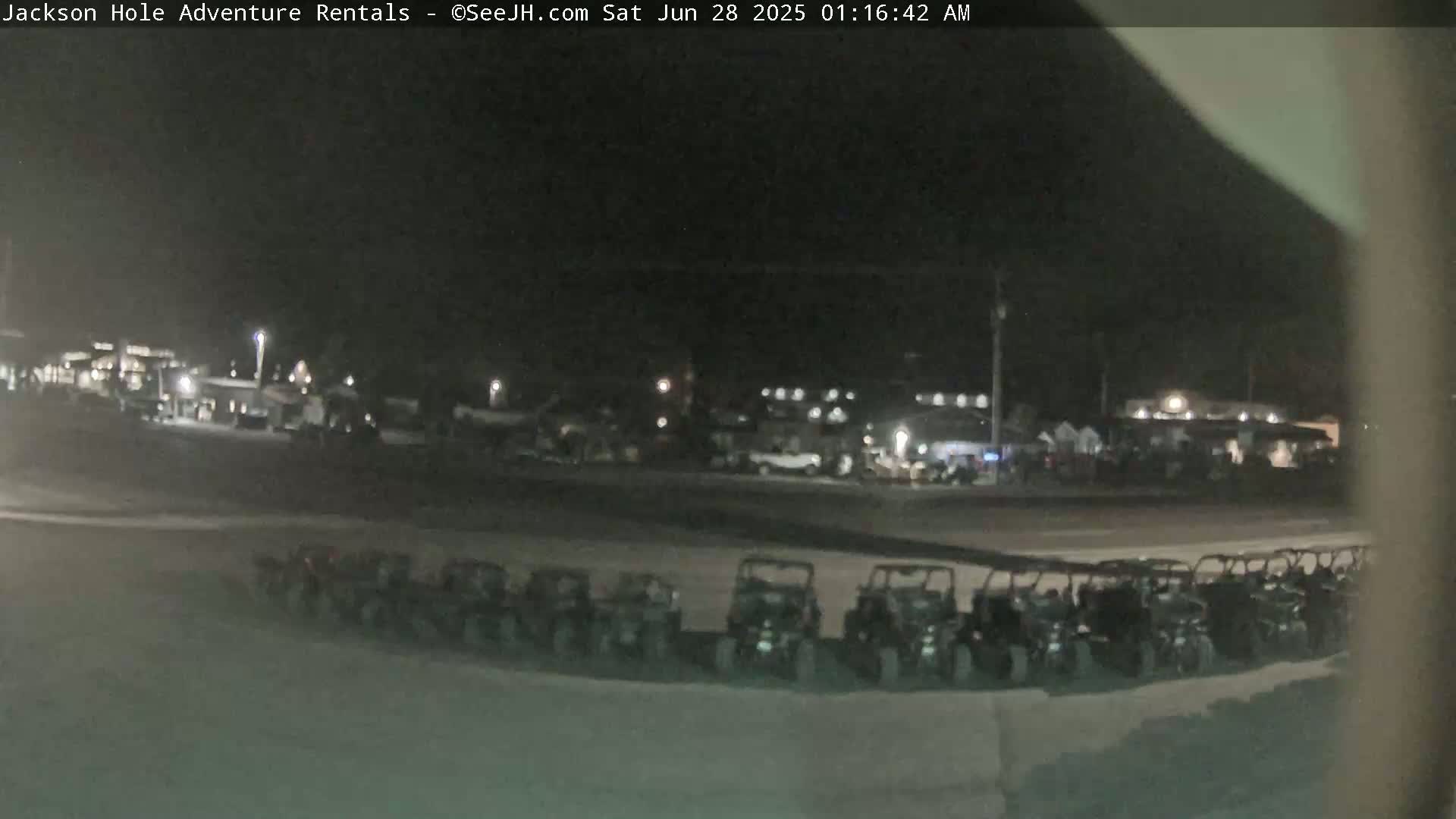 A nighttime view of a parking lot filled with all-terrain vehicles under a dark sky.