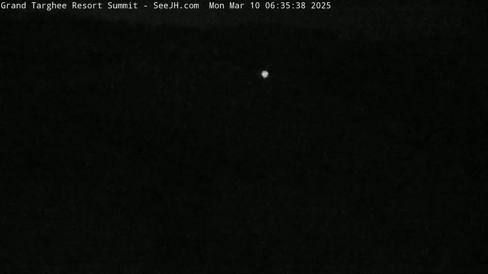 A single, small, bright light is visible in a dark, nighttime sky.