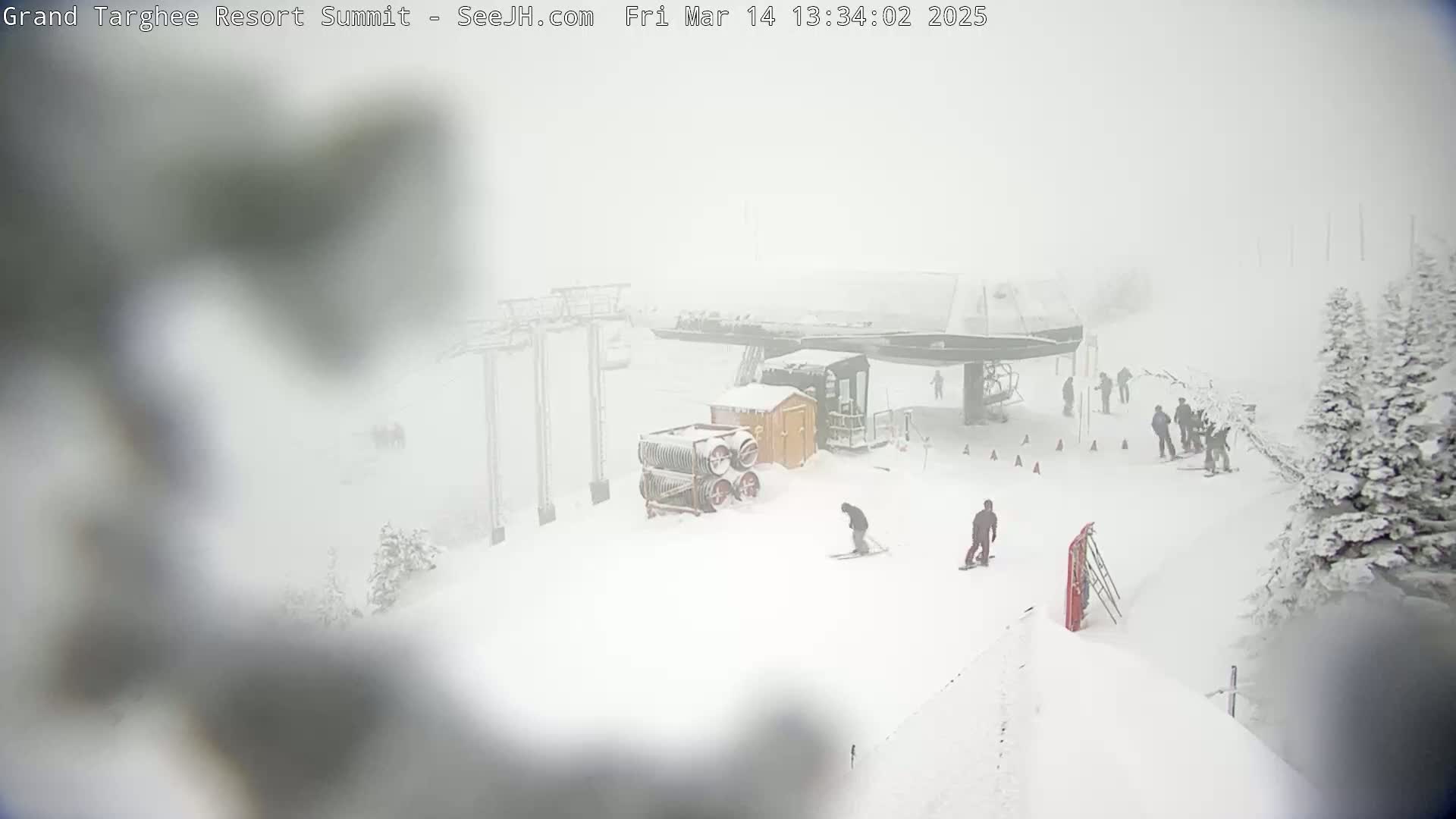 A snow-covered ski resort with several skiers and a chairlift is visible in heavy snow.