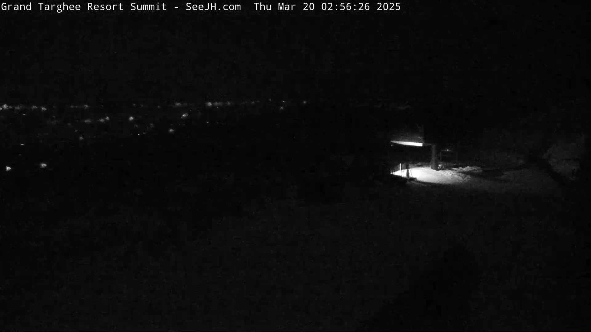 A nighttime, snow-covered landscape is visible, featuring a dimly lit structure and a distant array of faint lights.
