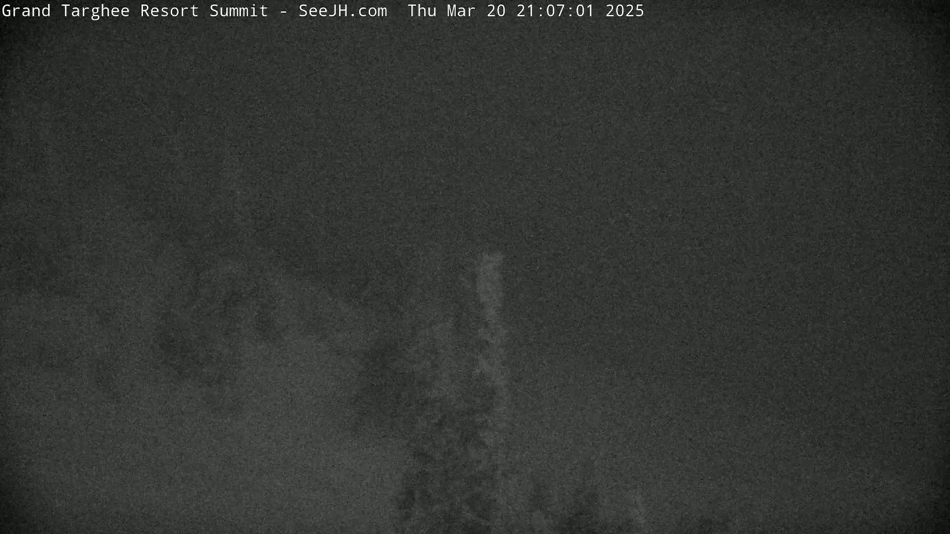 A dark, blurry nighttime image shows a dimly lit, snowy or foggy landscape.