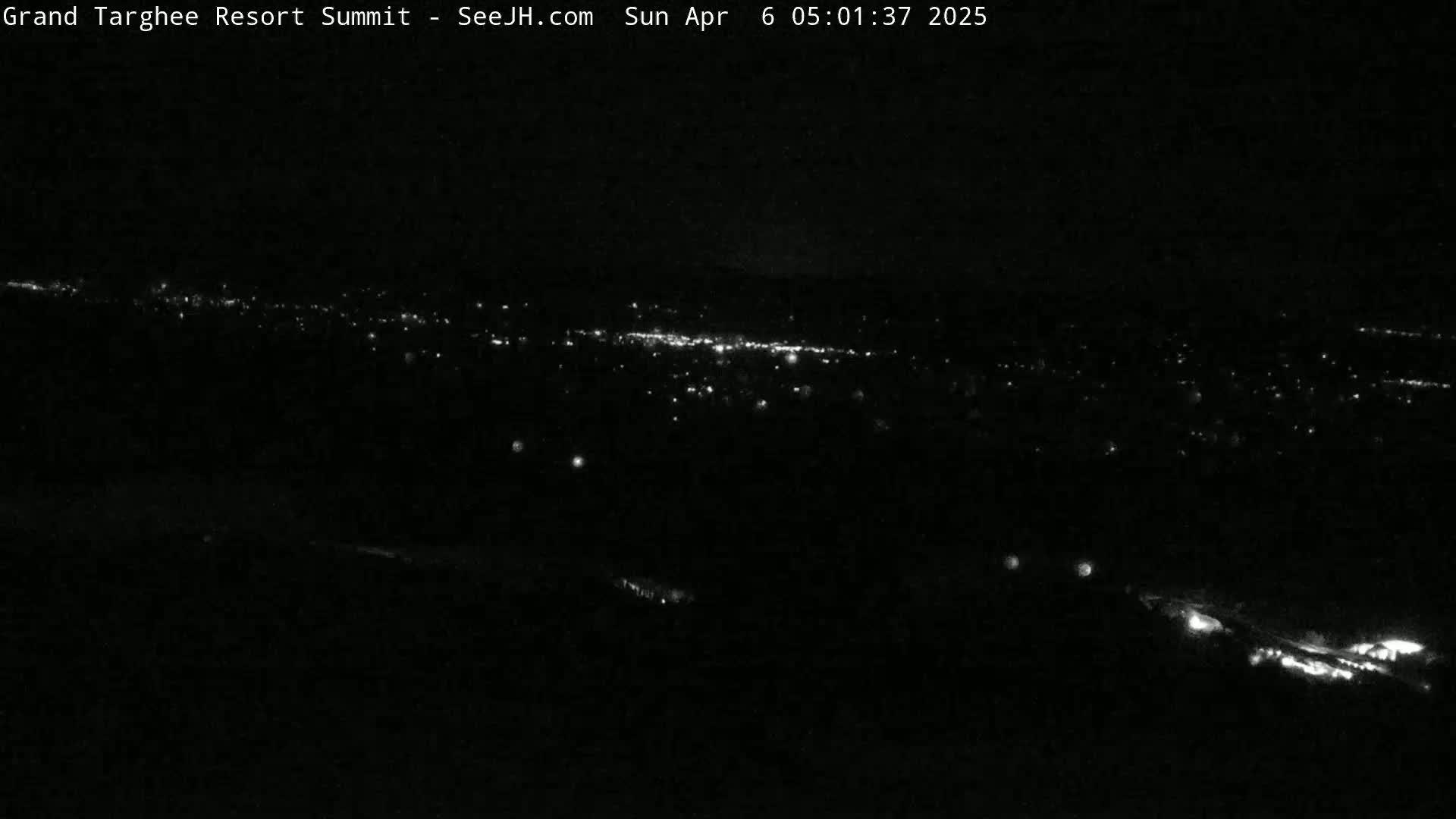 A nighttime long shot reveals a distant city illuminated by scattered lights.