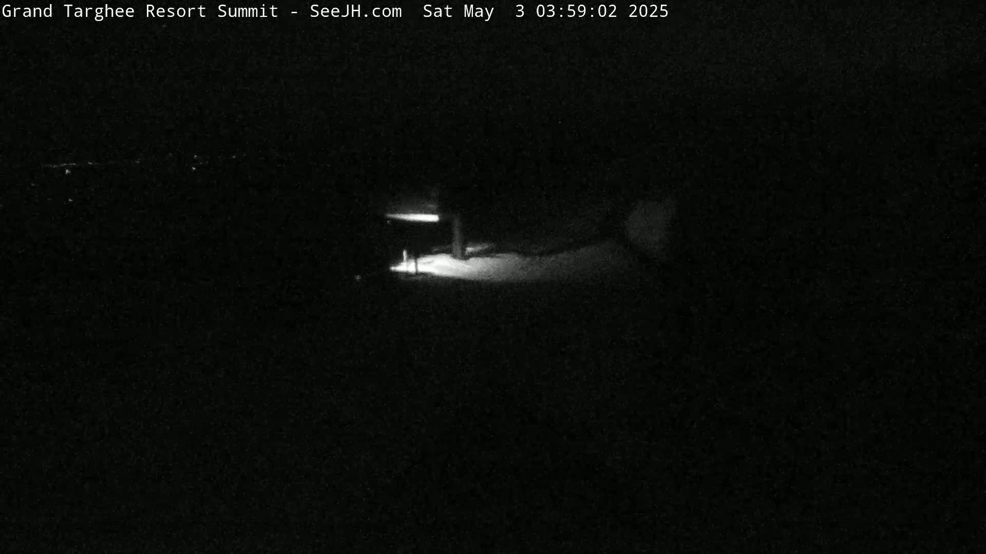 A dimly lit, snowy nighttime scene shows a post with a light above it.