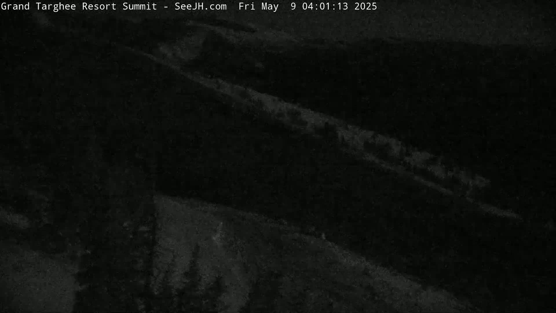A dark, nighttime view of a snow-covered mountain slope.