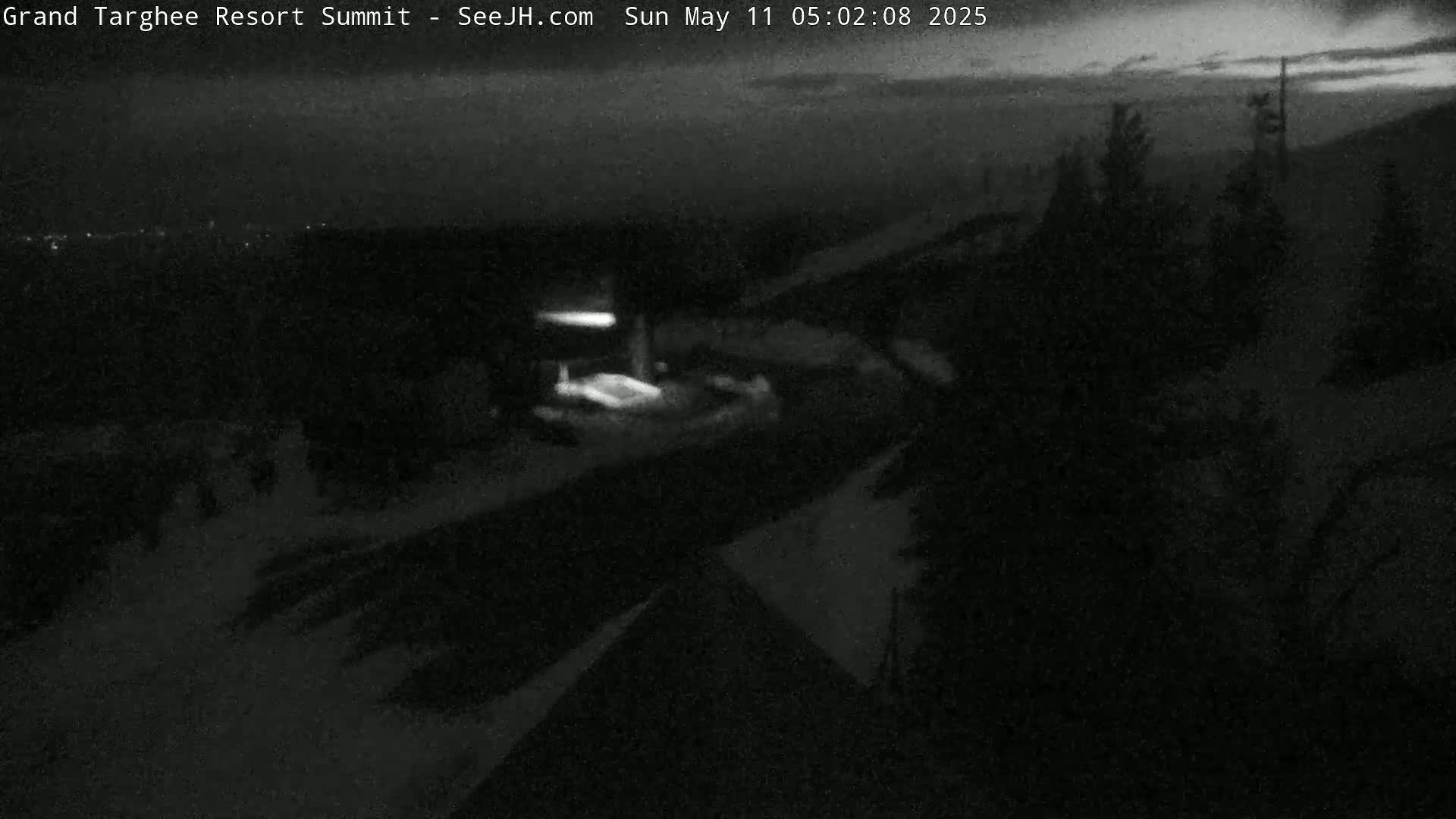 A nighttime, snow-covered landscape is visible, with a few lights and dark, silhouetted trees.