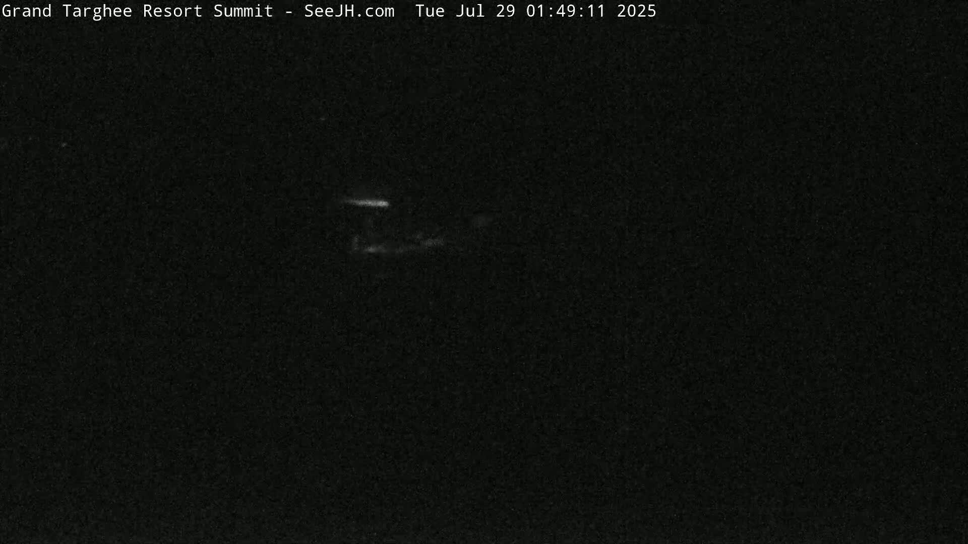 A dark, nighttime image shows a faintly illuminated structure in the distance.