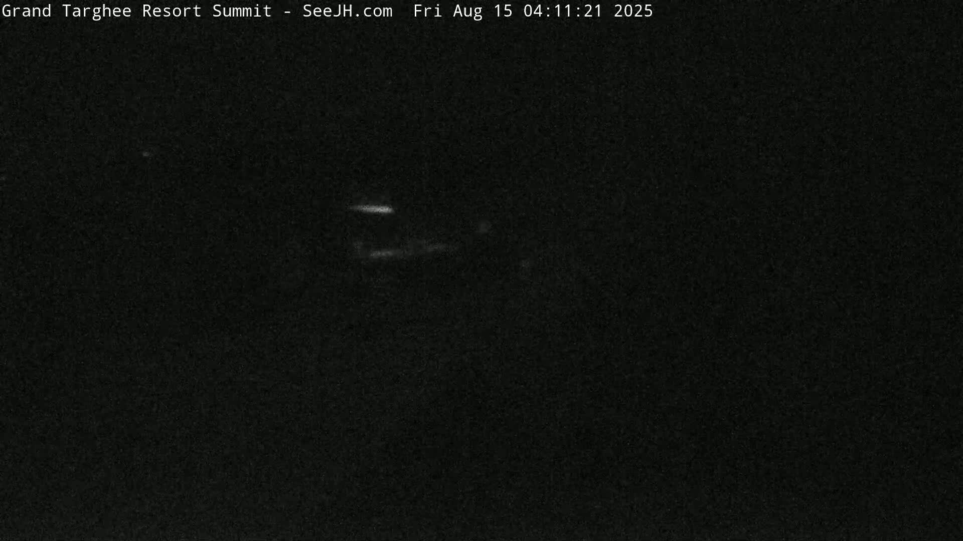 A dark, nighttime image shows a faintly illuminated structure in the distance.