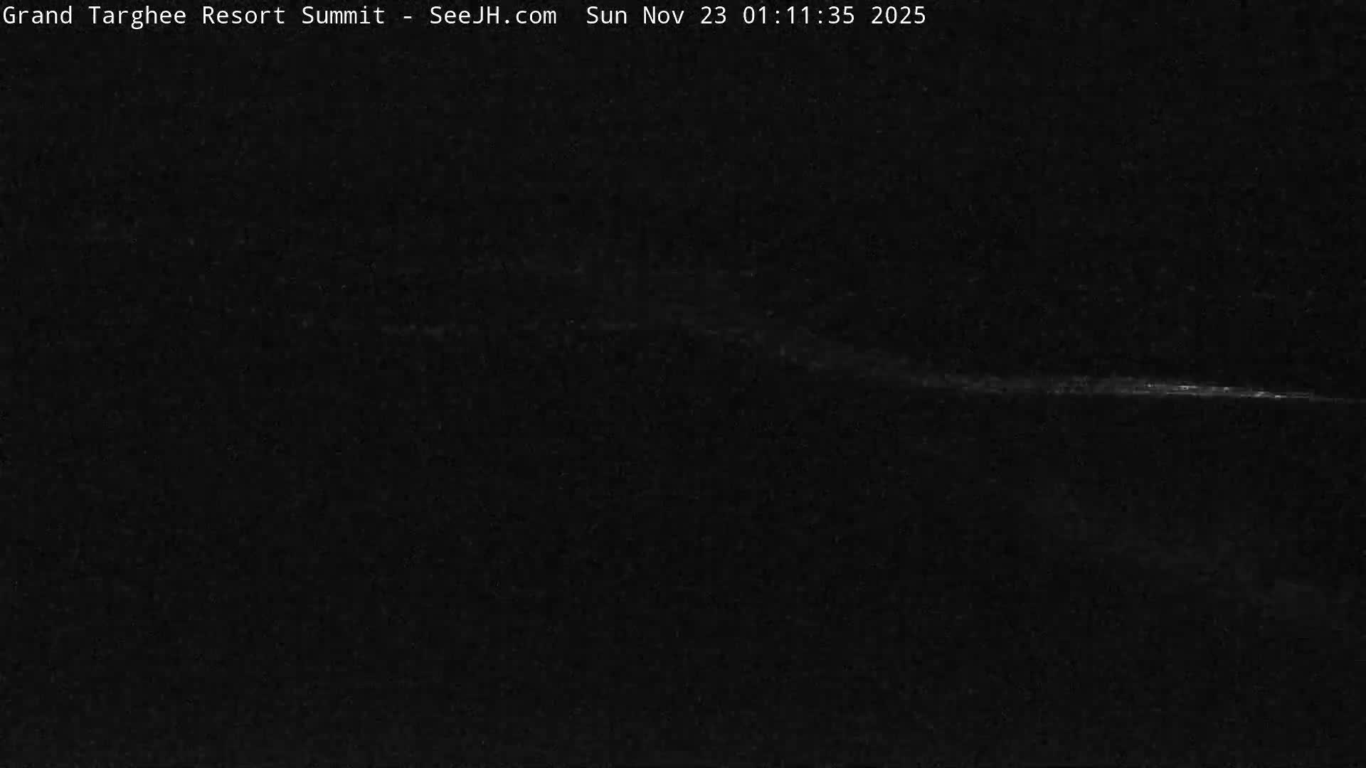 The image shows an extremely dark scene at night with a faint, blurry horizontal streak of light in the lower right, suggesting very low visibility.
