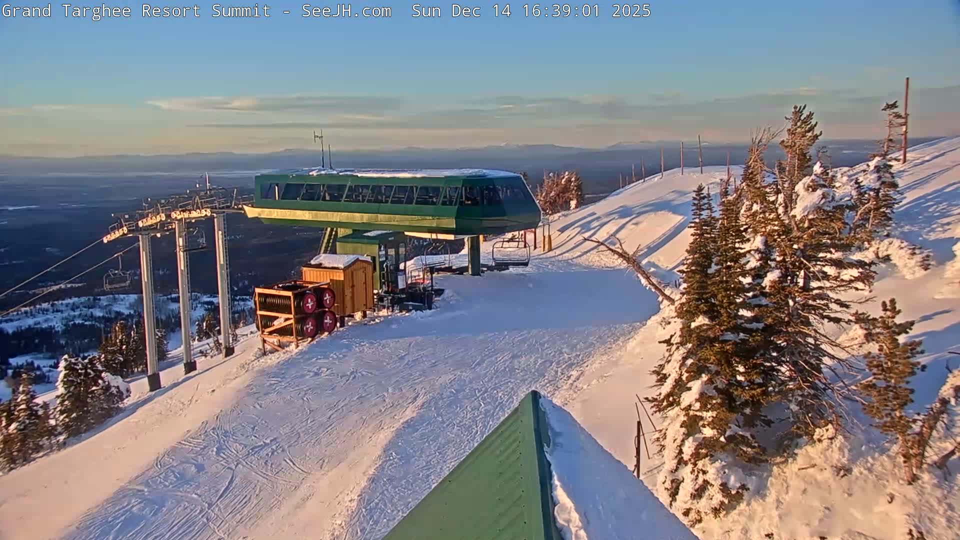A nighttime view of a snow-covered mountain resort reveals a brightly lit building and snow-laden trees under heavy snowfall or blizzard conditions.