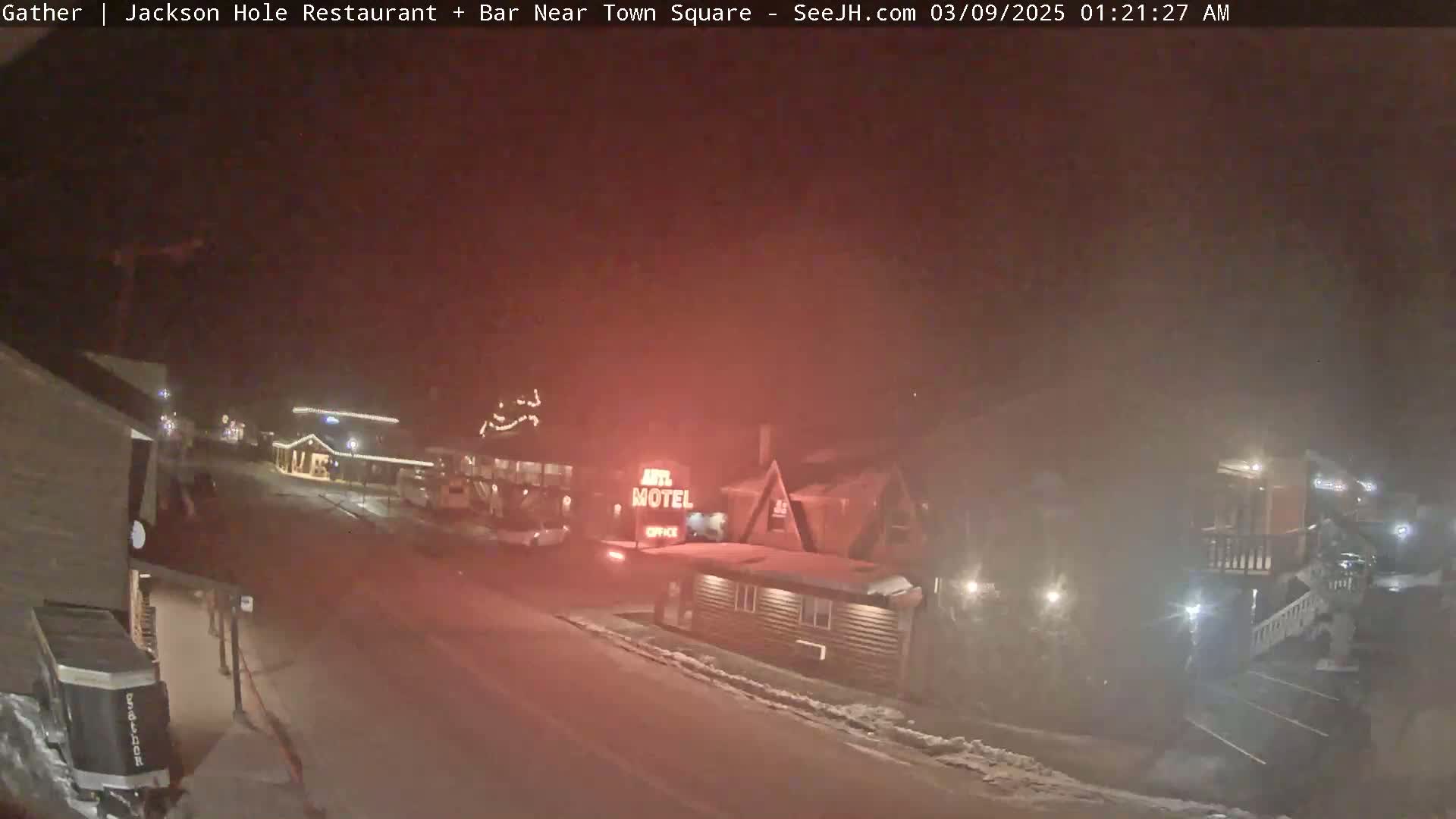 A nighttime street scene shows a motel and other buildings under hazy, possibly snowy conditions.