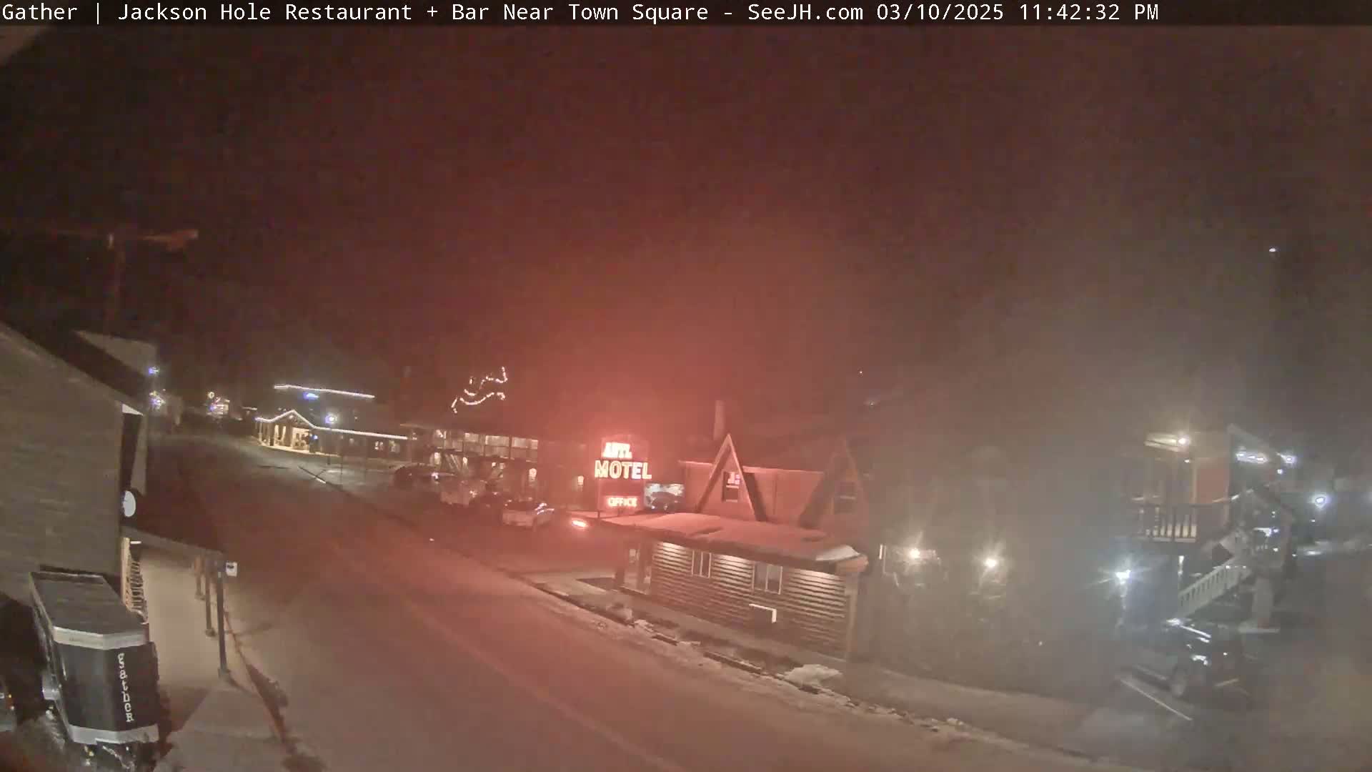 A nighttime street scene shows a motel and other buildings under hazy, snowy conditions.