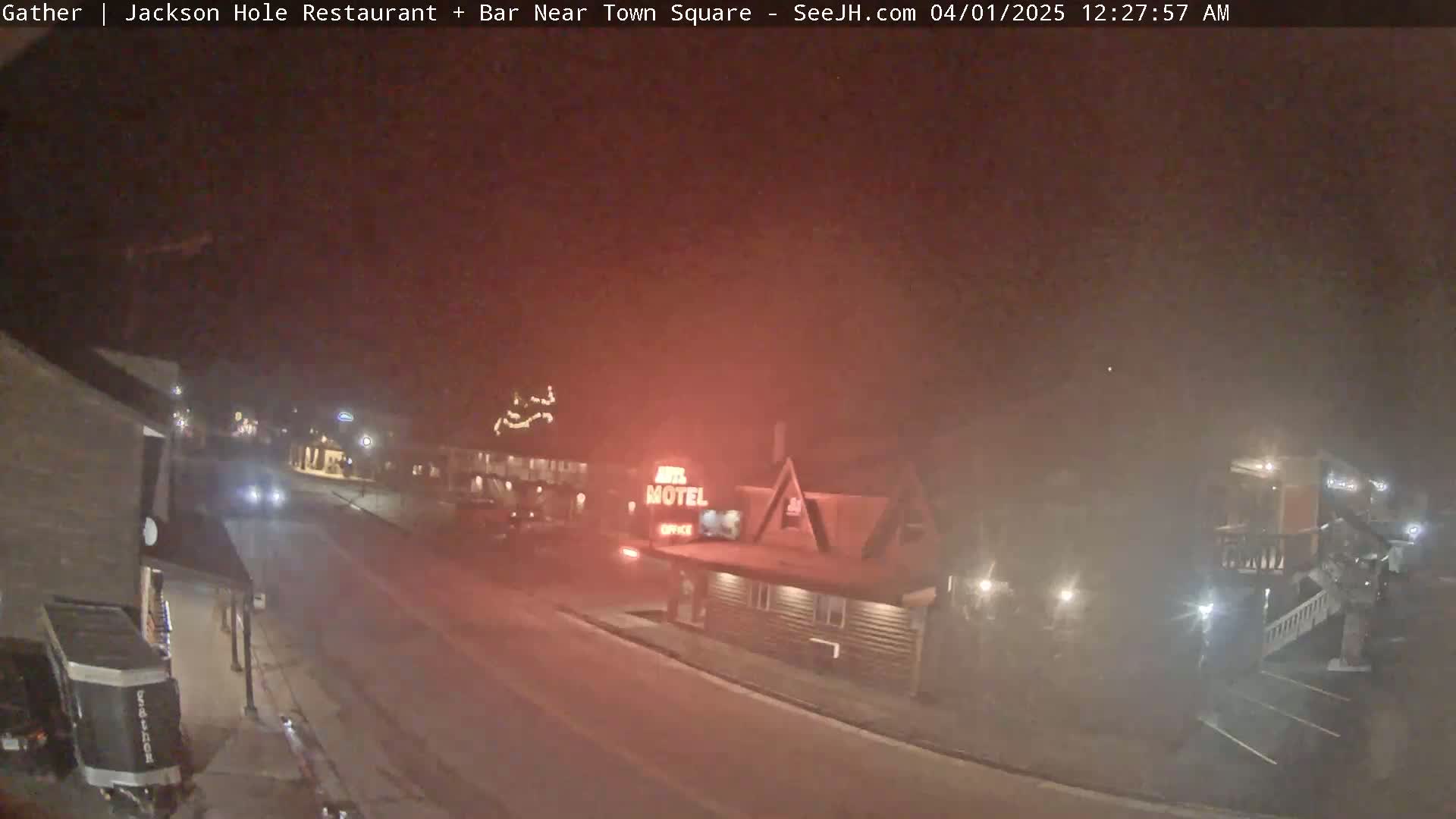 A nighttime street scene shows a motel and other buildings shrouded in fog.