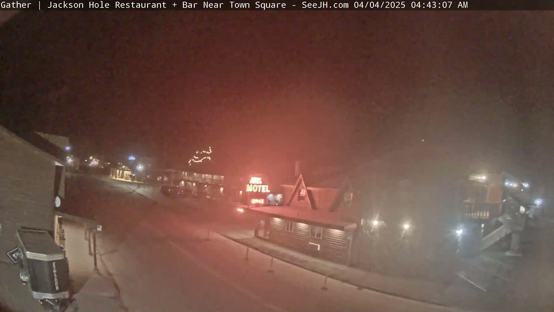 A nighttime, hazy view of a street scene showing a motel and other buildings, with snow or ice visible on the ground.