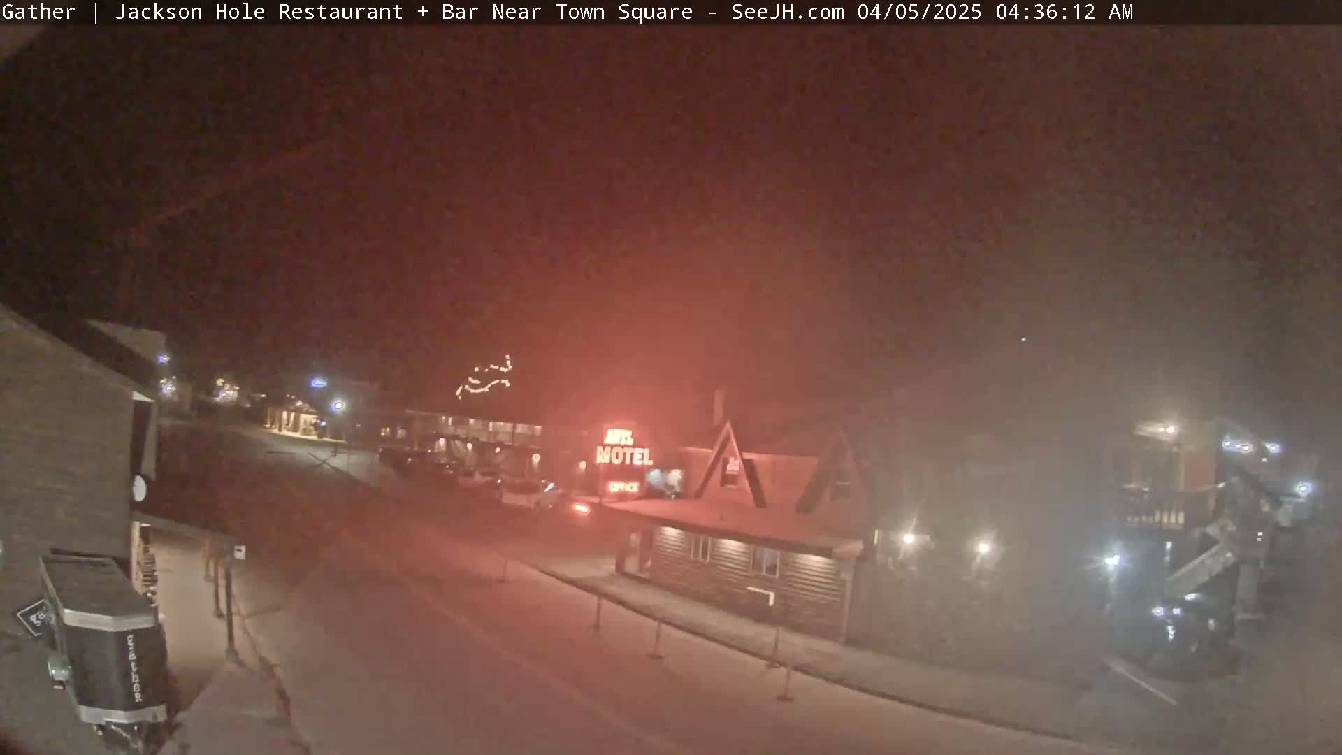 A nighttime, hazy view of a street scene showing a motel and other buildings with minimal traffic.