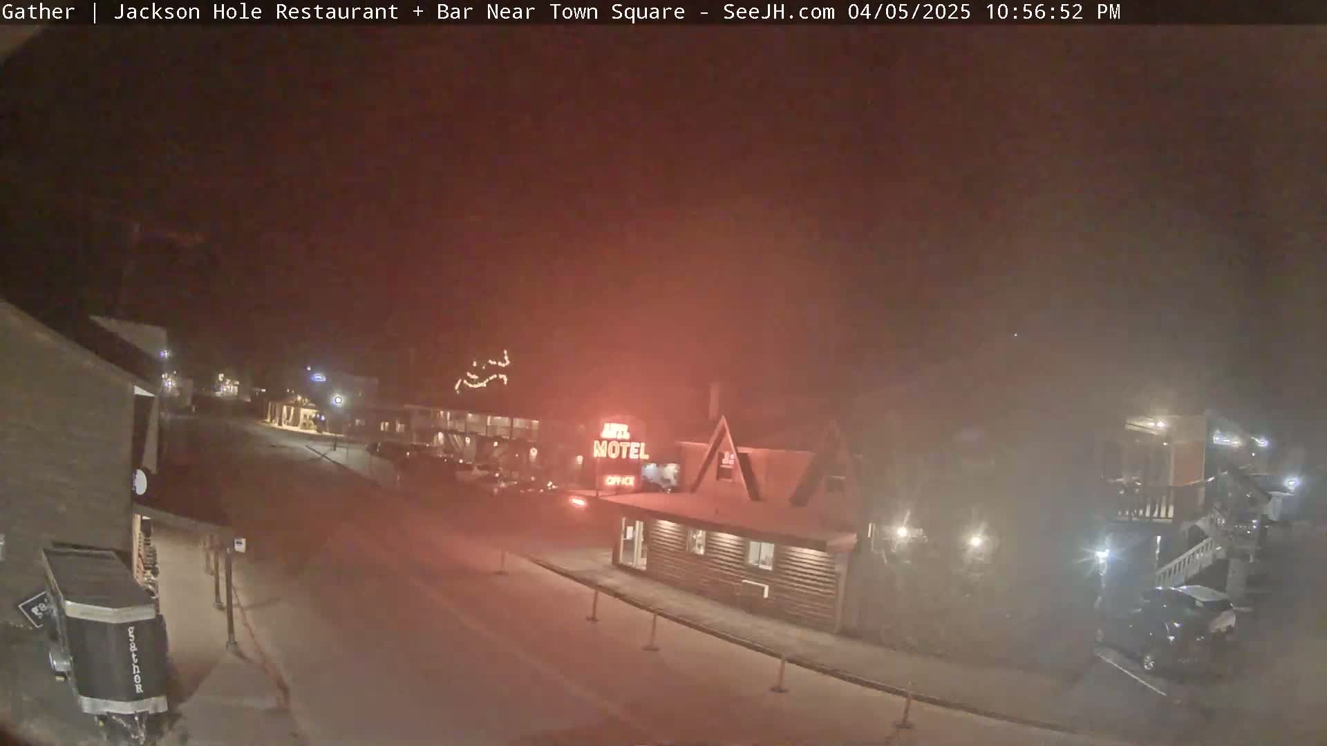 A nighttime street scene, obscured by haze, shows a motel and other buildings with sparse vehicle traffic.