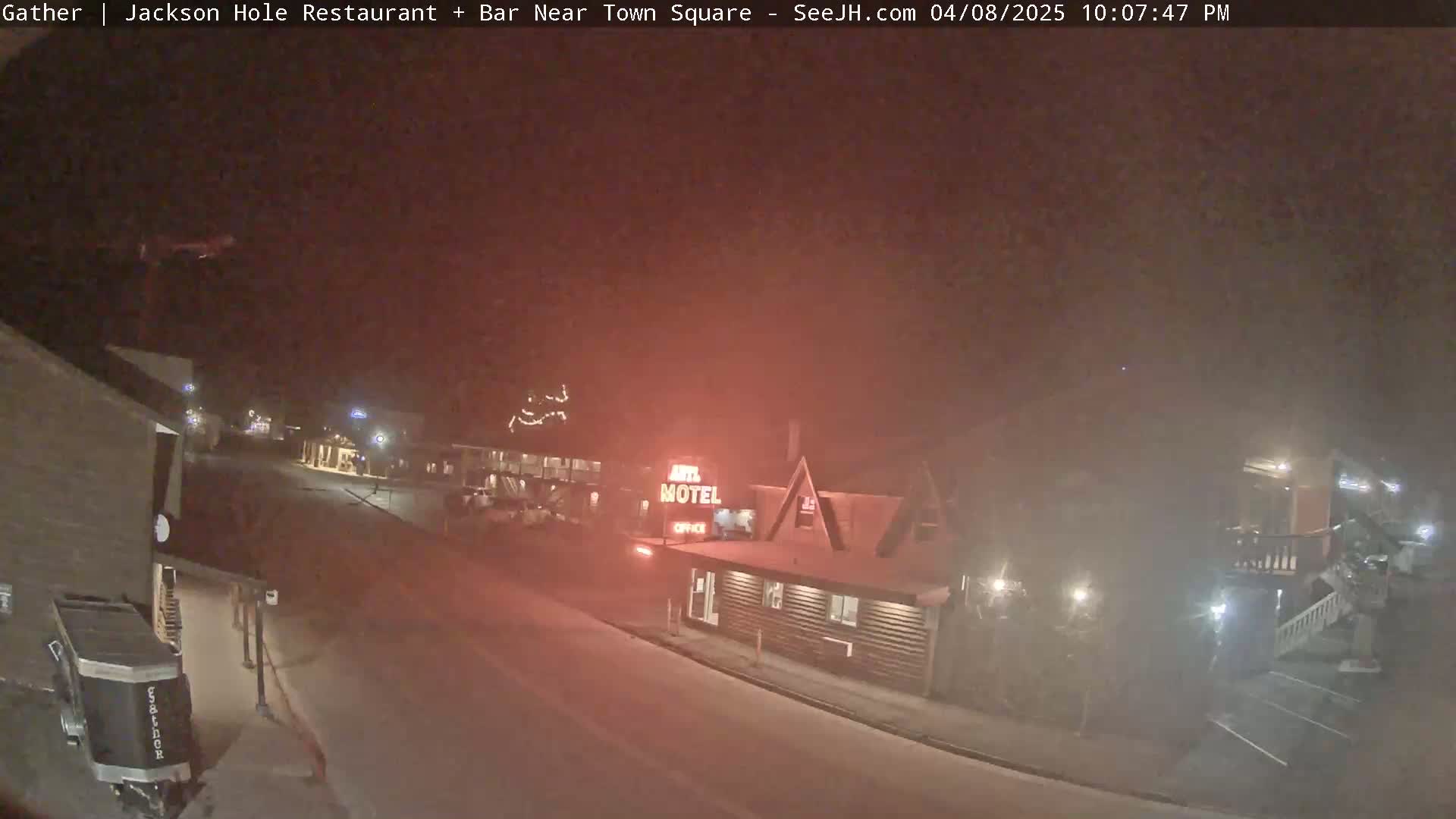 A nighttime street scene shows a motel and other buildings under hazy or foggy conditions.
