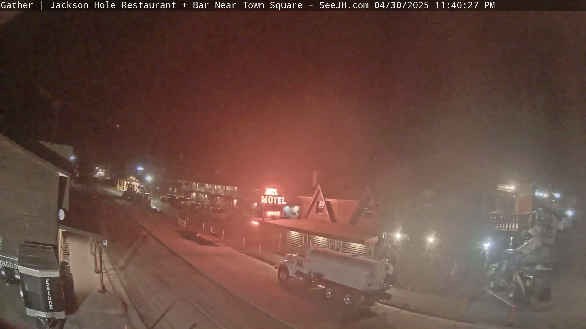 A nighttime street scene shows a motel and other buildings under hazy, possibly snowy conditions, with a truck parked nearby.