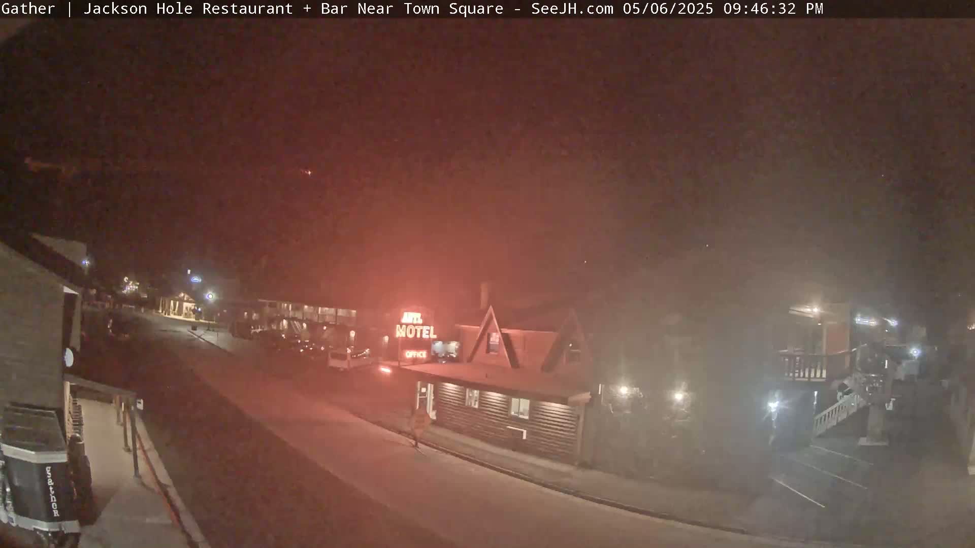 A nighttime street scene shows a motel and other buildings under hazy, possibly foggy conditions.